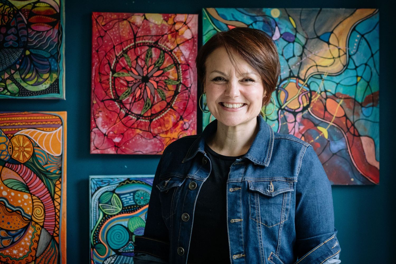 Close-up outdoor portrait of someone with flipped shoulder-length hair and bangs wearing a patterned navy blue shirt.