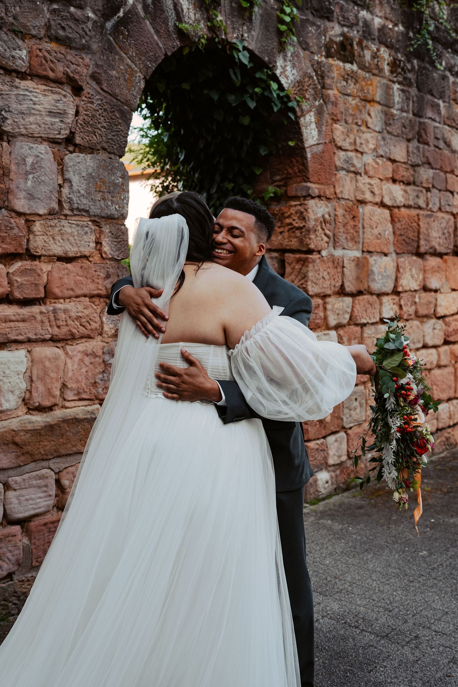 A romantic couple in white clothing shares an intimate moment in a wooded setting during golden hour.