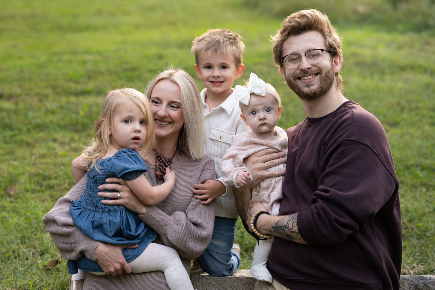 Family portrait session with young children in casual attire outdoors.