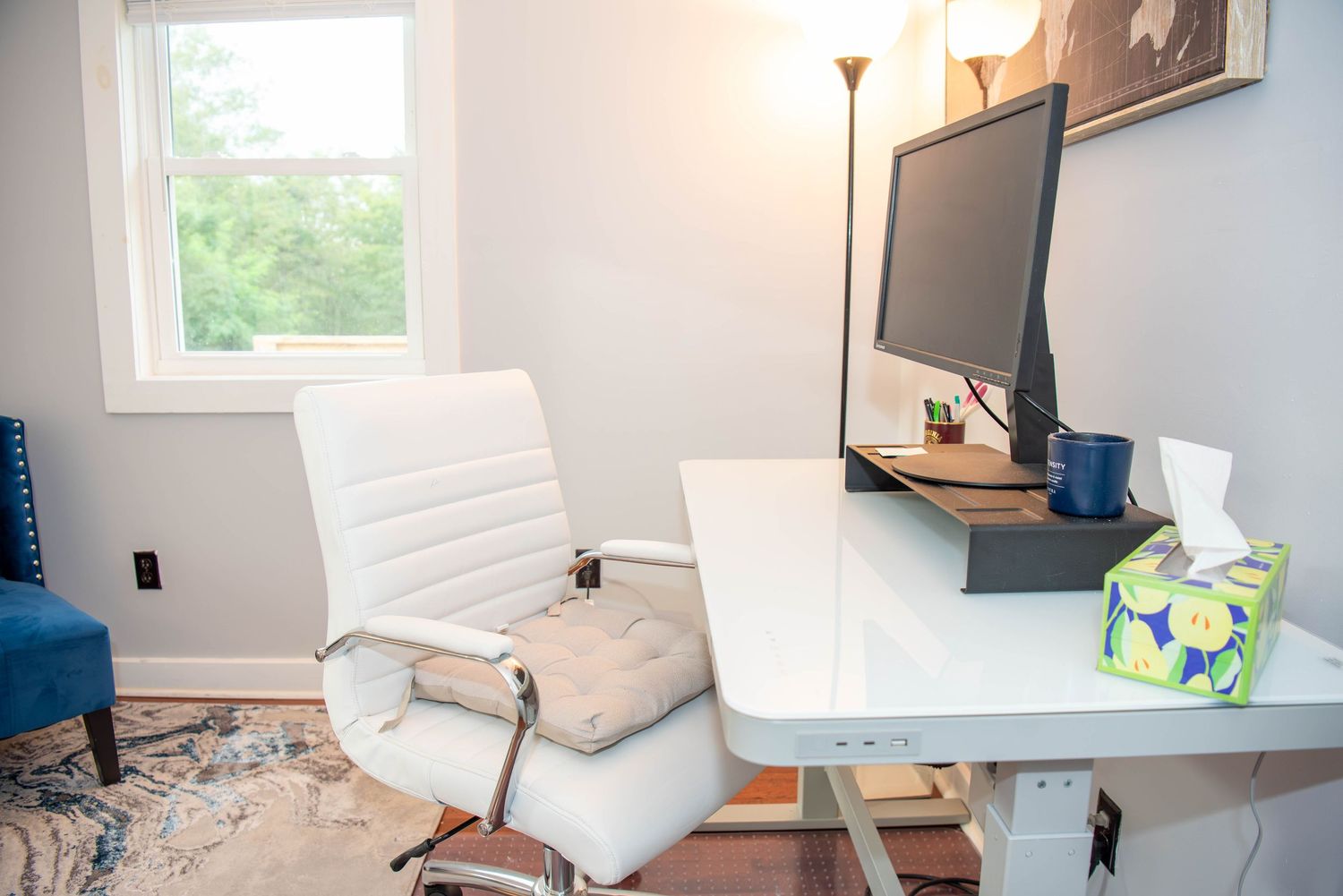 Modern white office space with natural light featuring a desk, chair, and window.