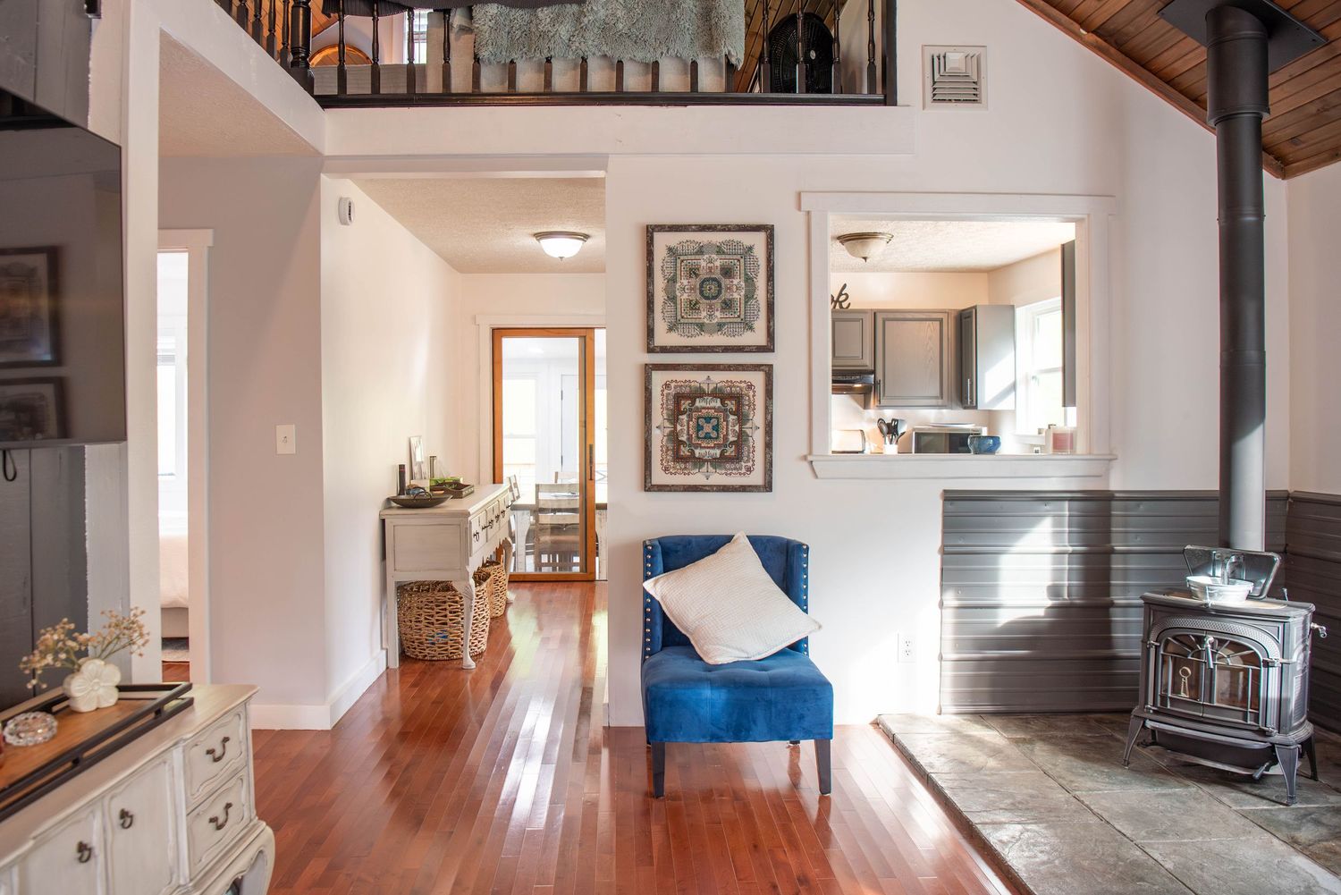 Open concept living space with hardwood floors, white walls and staircase leading to upper level.