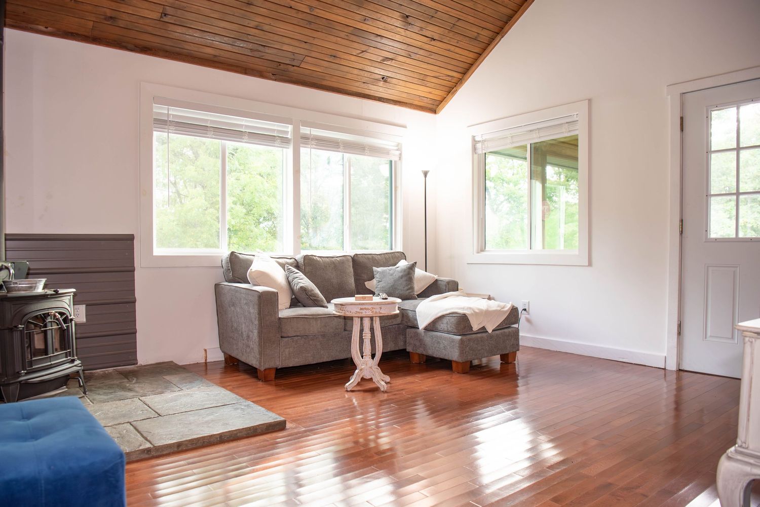 A bright modern room with wood ceiling panels, white walls, and large windows letting in natural light.