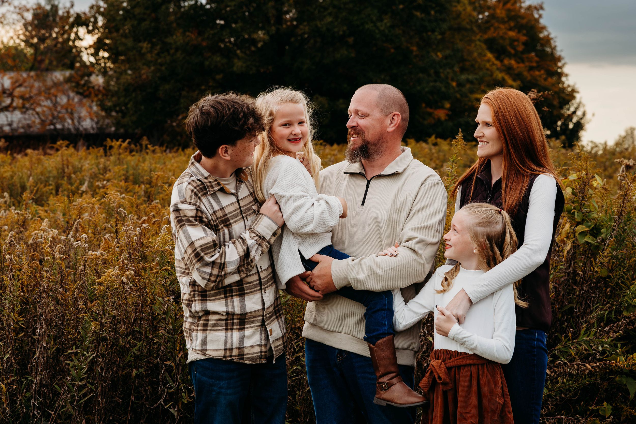 A loving family enjoys quality time together outdoors during a golden autumn photoshoot in a natural setting.