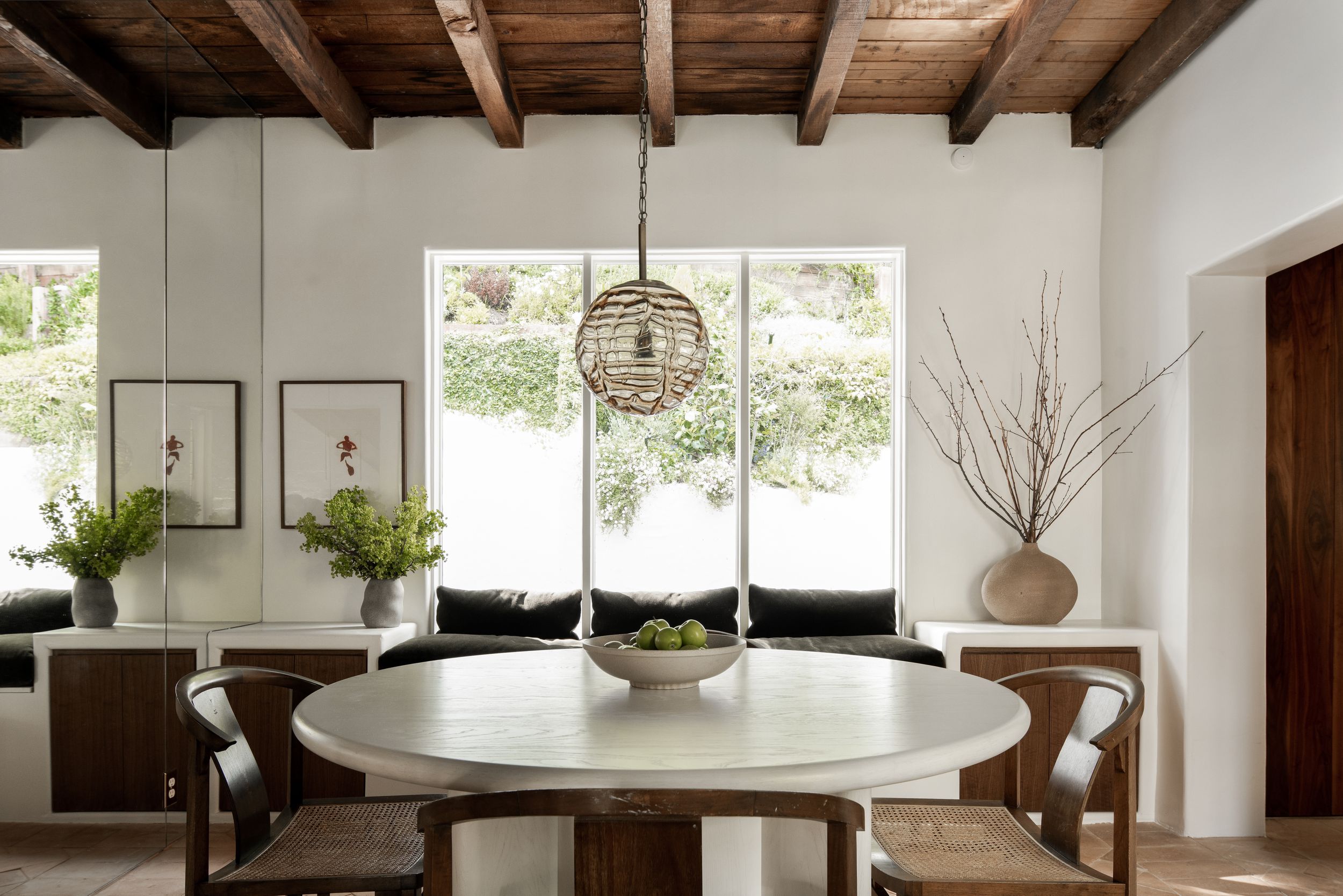 Modern farmhouse kitchen features exposed wooden beams, pendant lights, and large windows creating a bright airy space.
