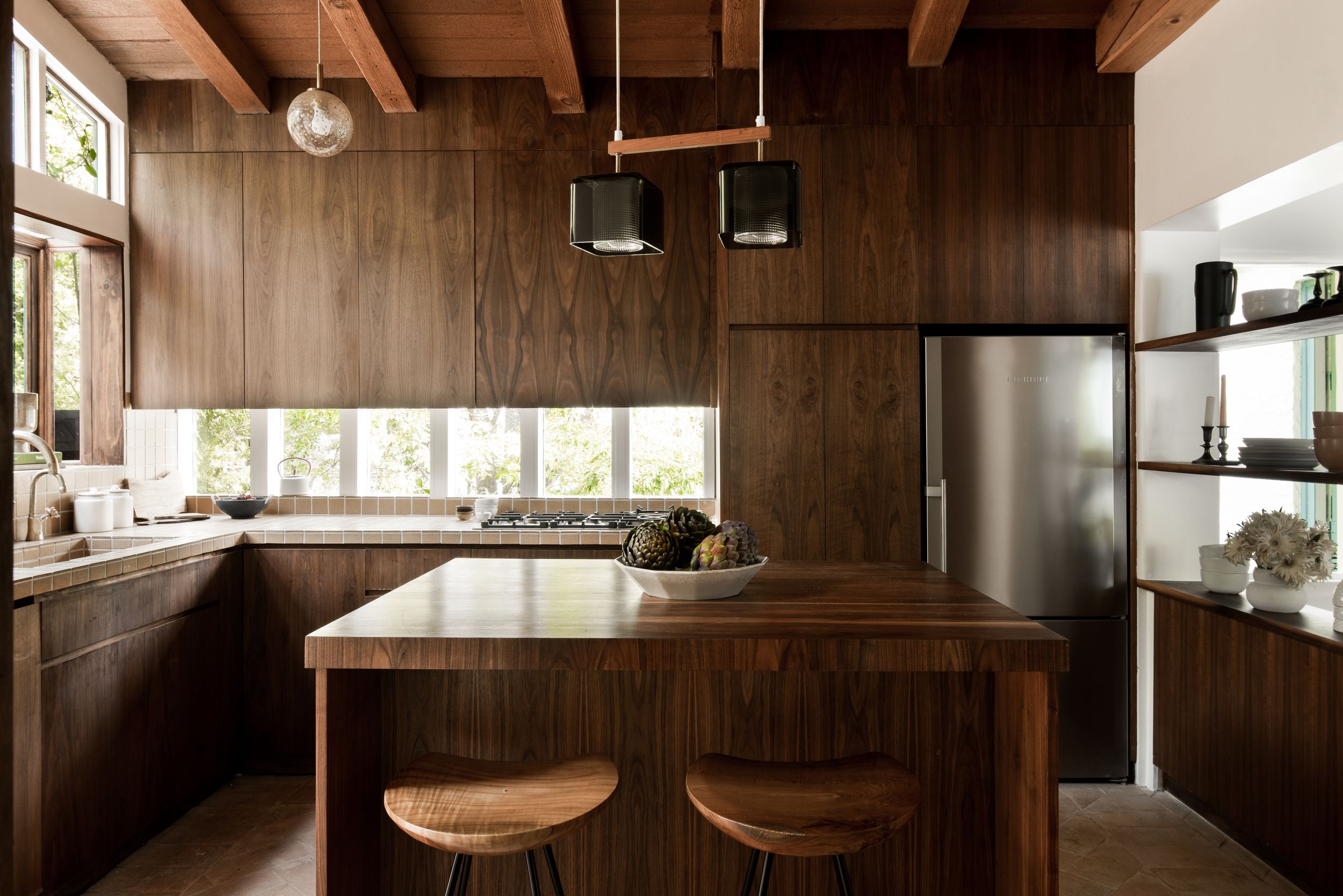 Warm wood paneled interior of a modern home with large windows and natural light streaming in.