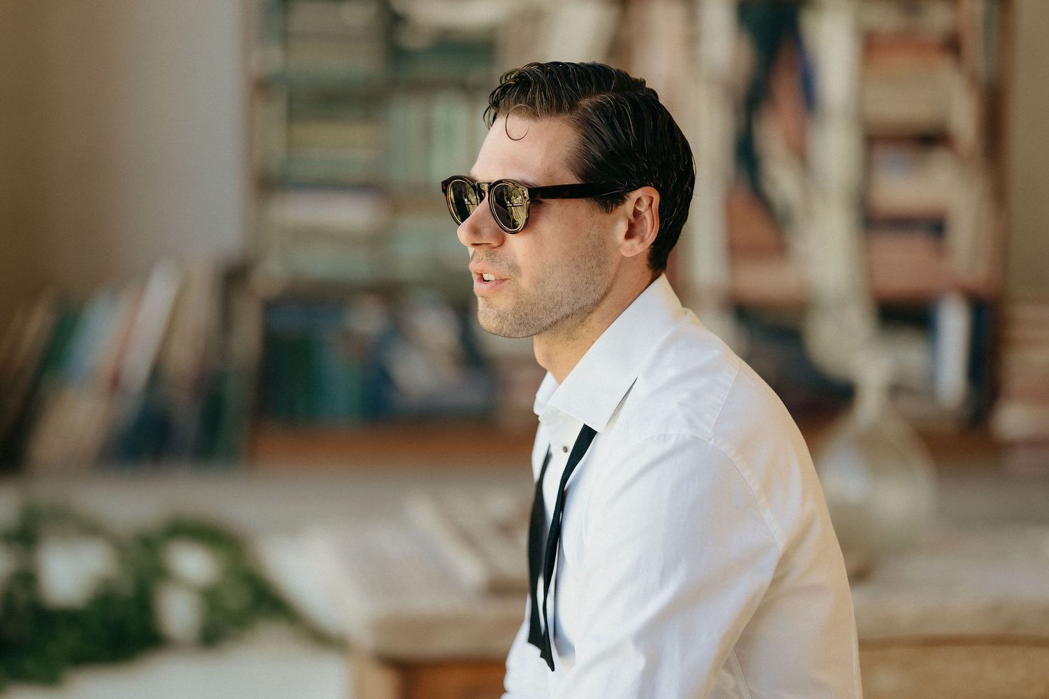 A person in a white dress shirt and sunglasses poses in various positions against a blurred background.