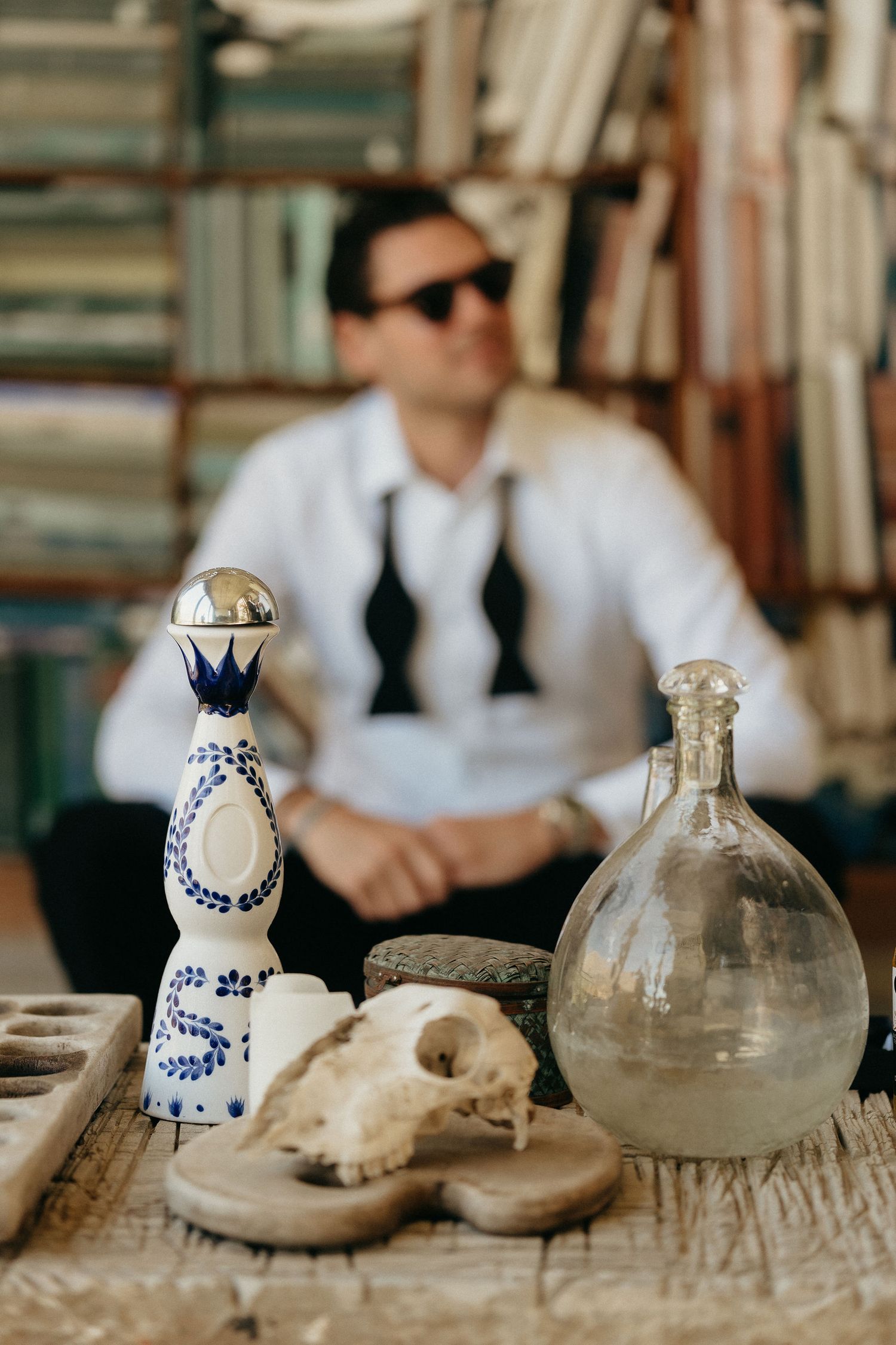 A series of vintage glass bottles and ceramic decorative pieces arranged on a rustic wooden surface in a blurred sequence.