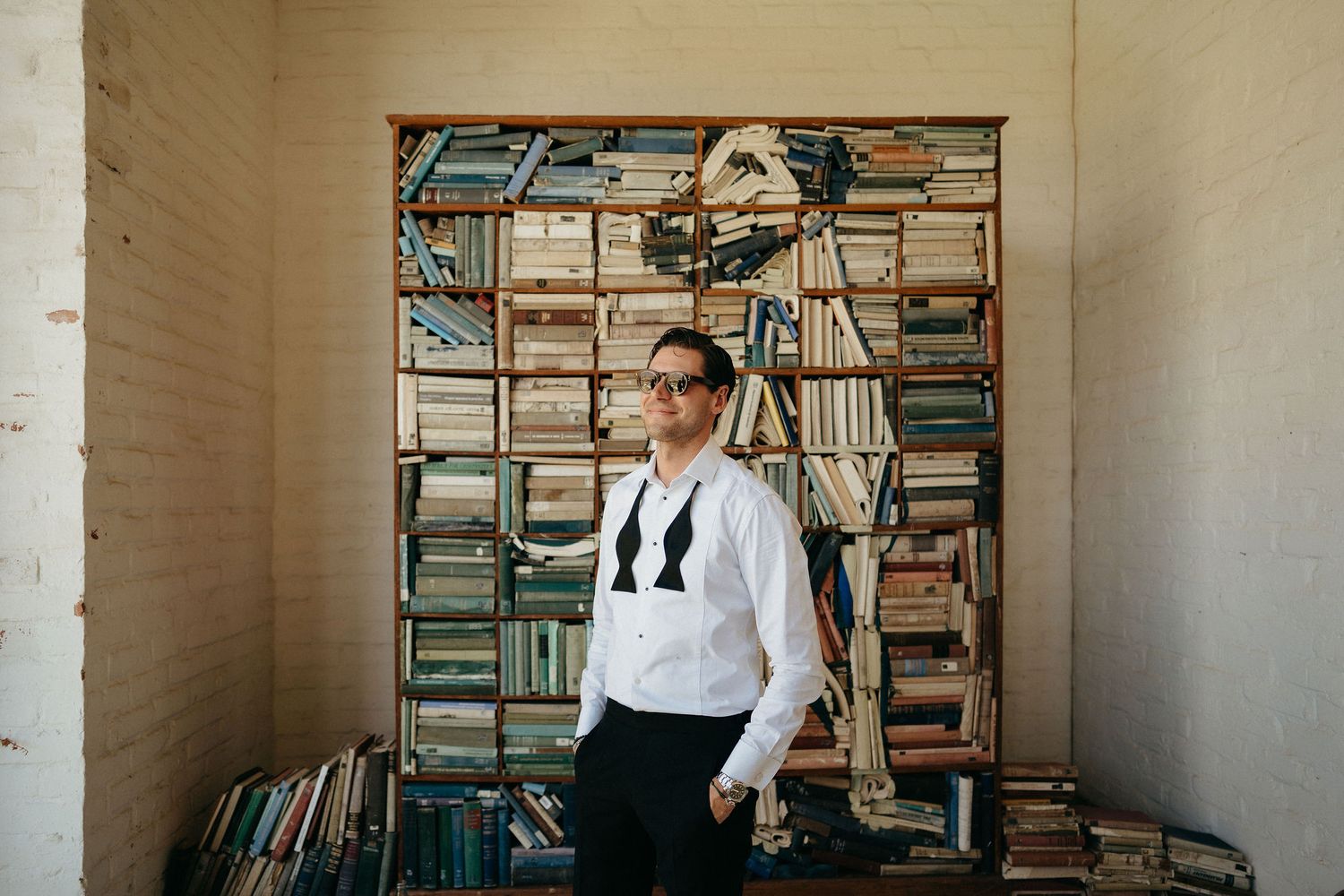 Person browsing books in a cozy library corner filled with stacked shelves and natural lighting.