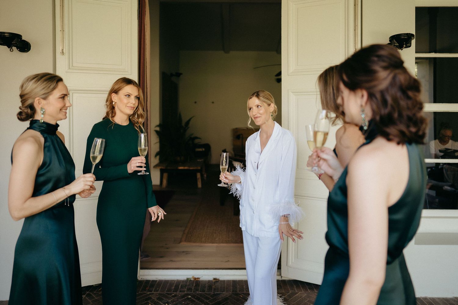 A group of wedding guests in black and white dresses gather in a line for a photo at an indoor reception.