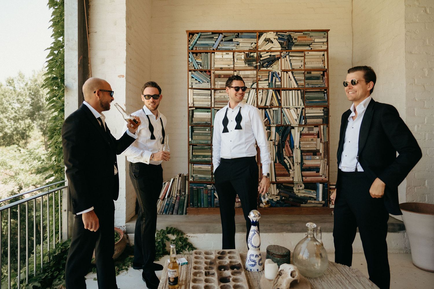A group in formal attire poses together in a bright interior space with bookshelves in the background.