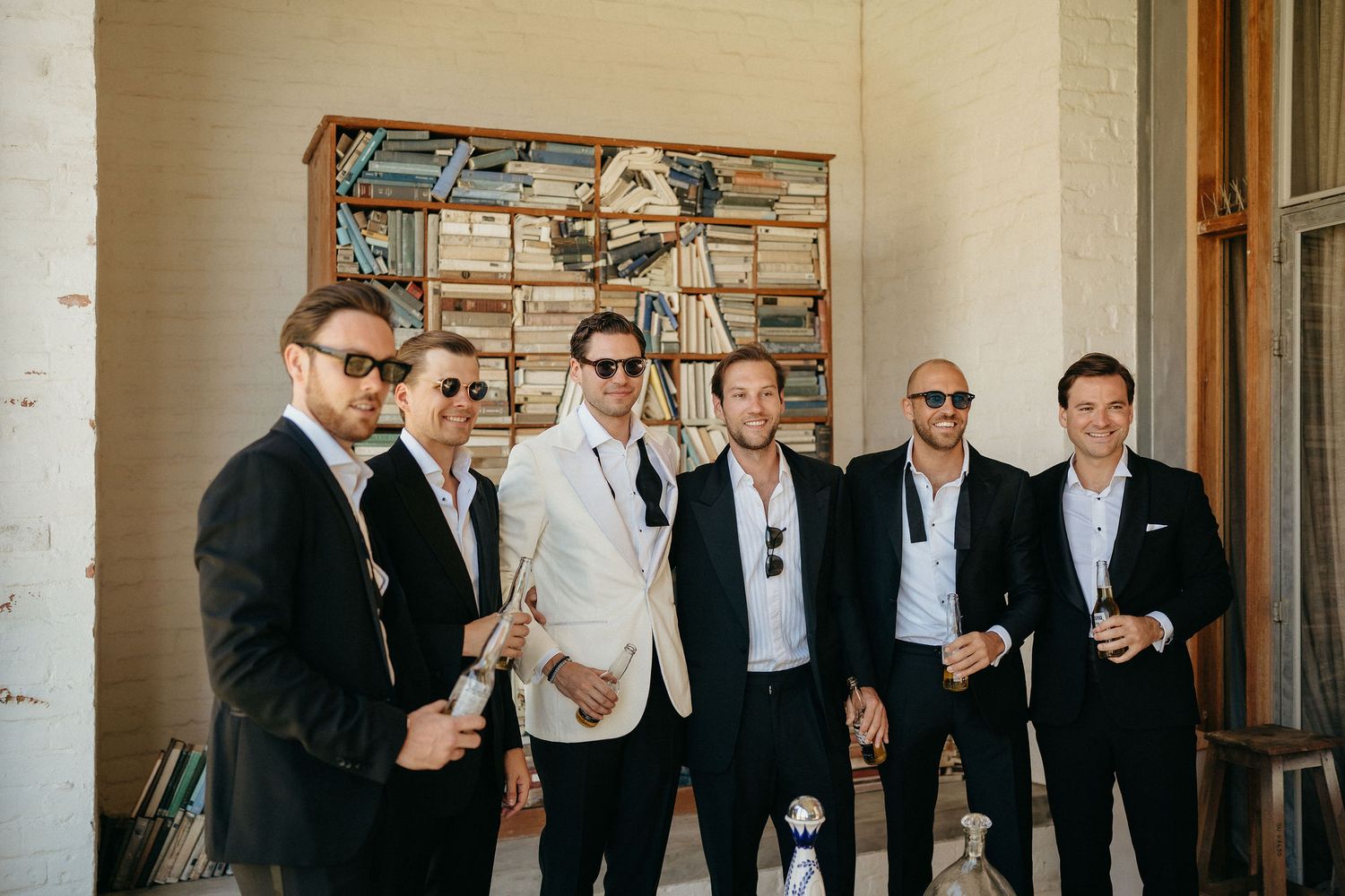A group of people in formal black and white attire gather in a rustic indoor setting for a celebratory event.