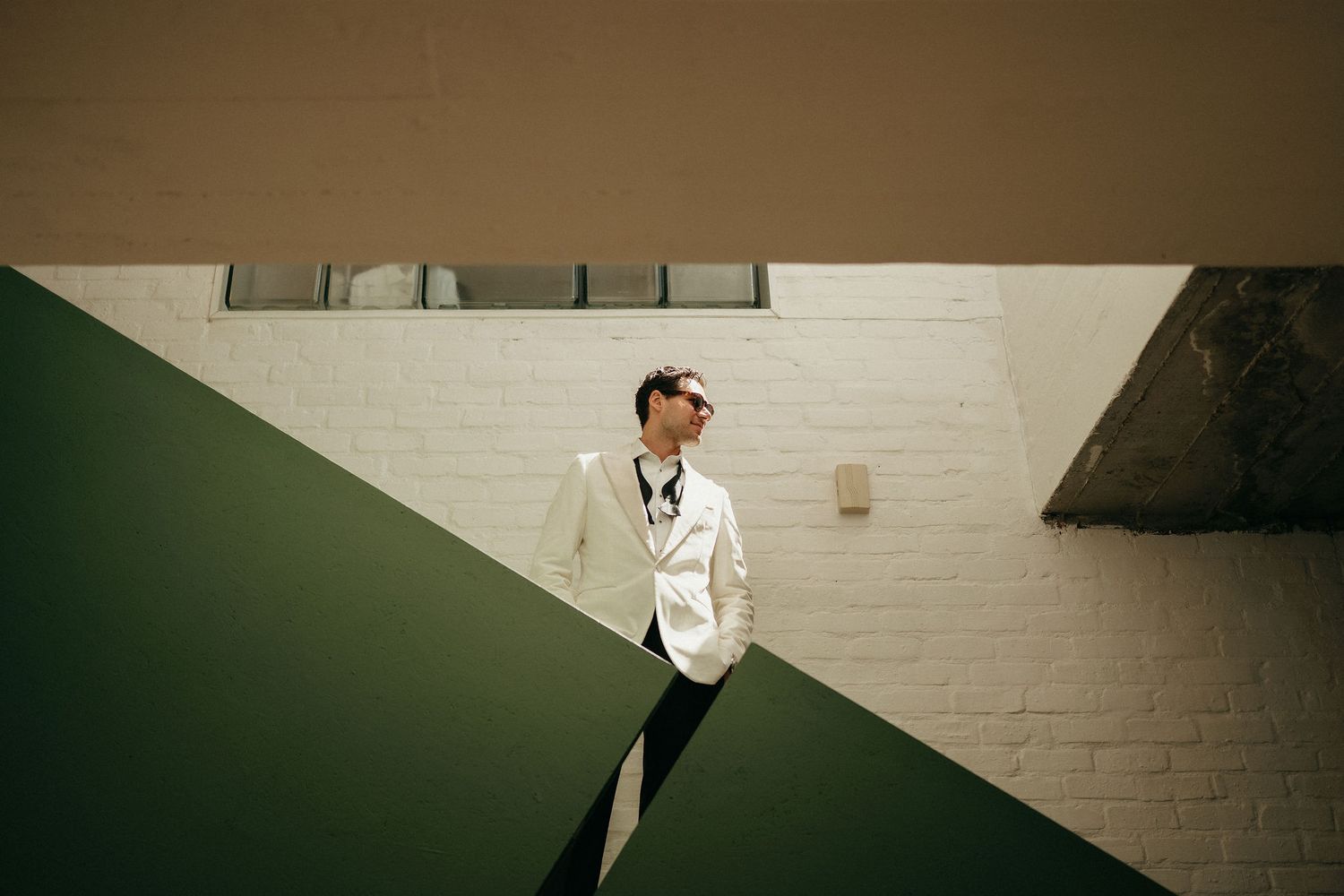 A series of black and white photographs showing a person in formal attire dancing and posing against a white brick wall.