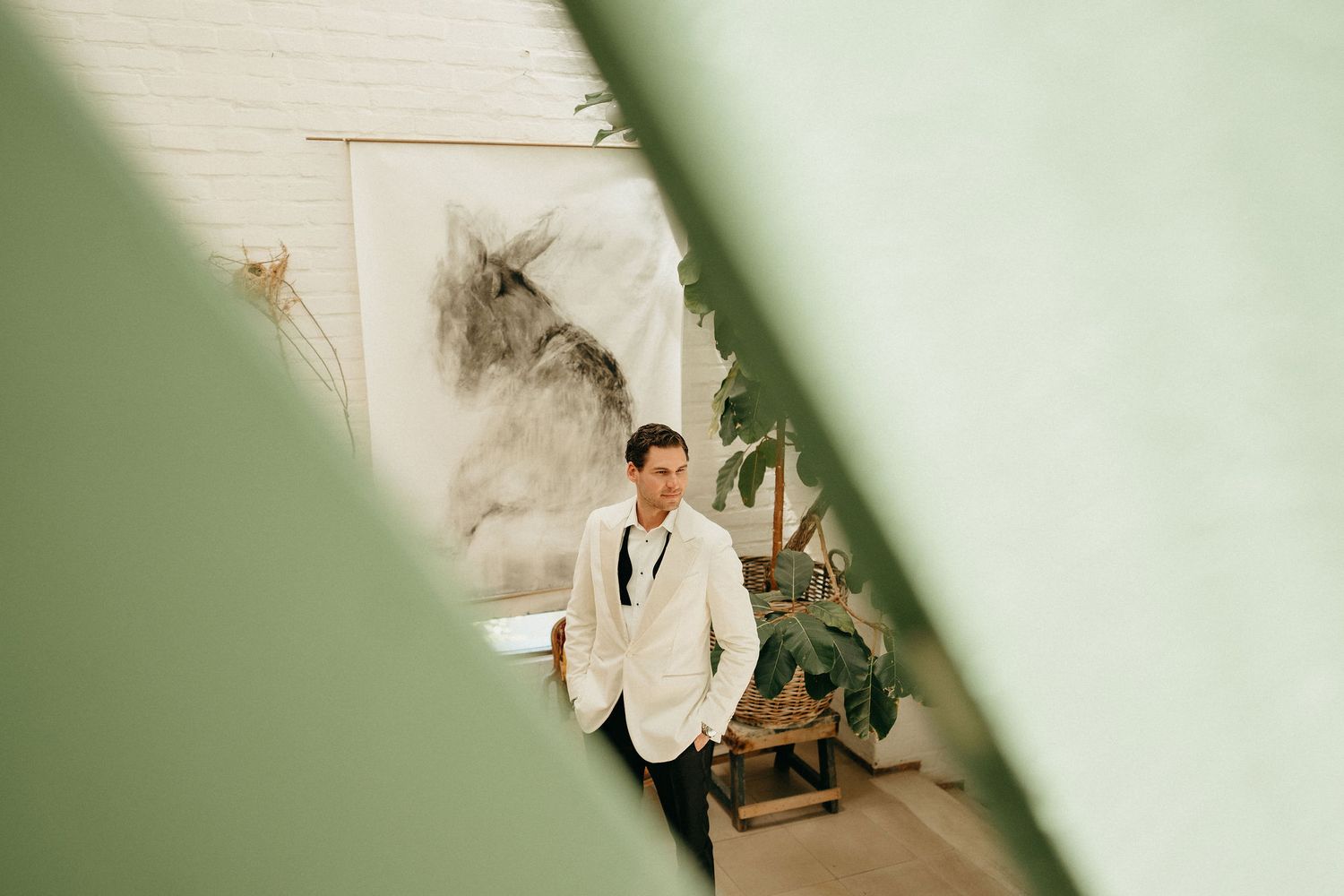 A person in a white lab coat stands against a green wall while holding a tablet device.