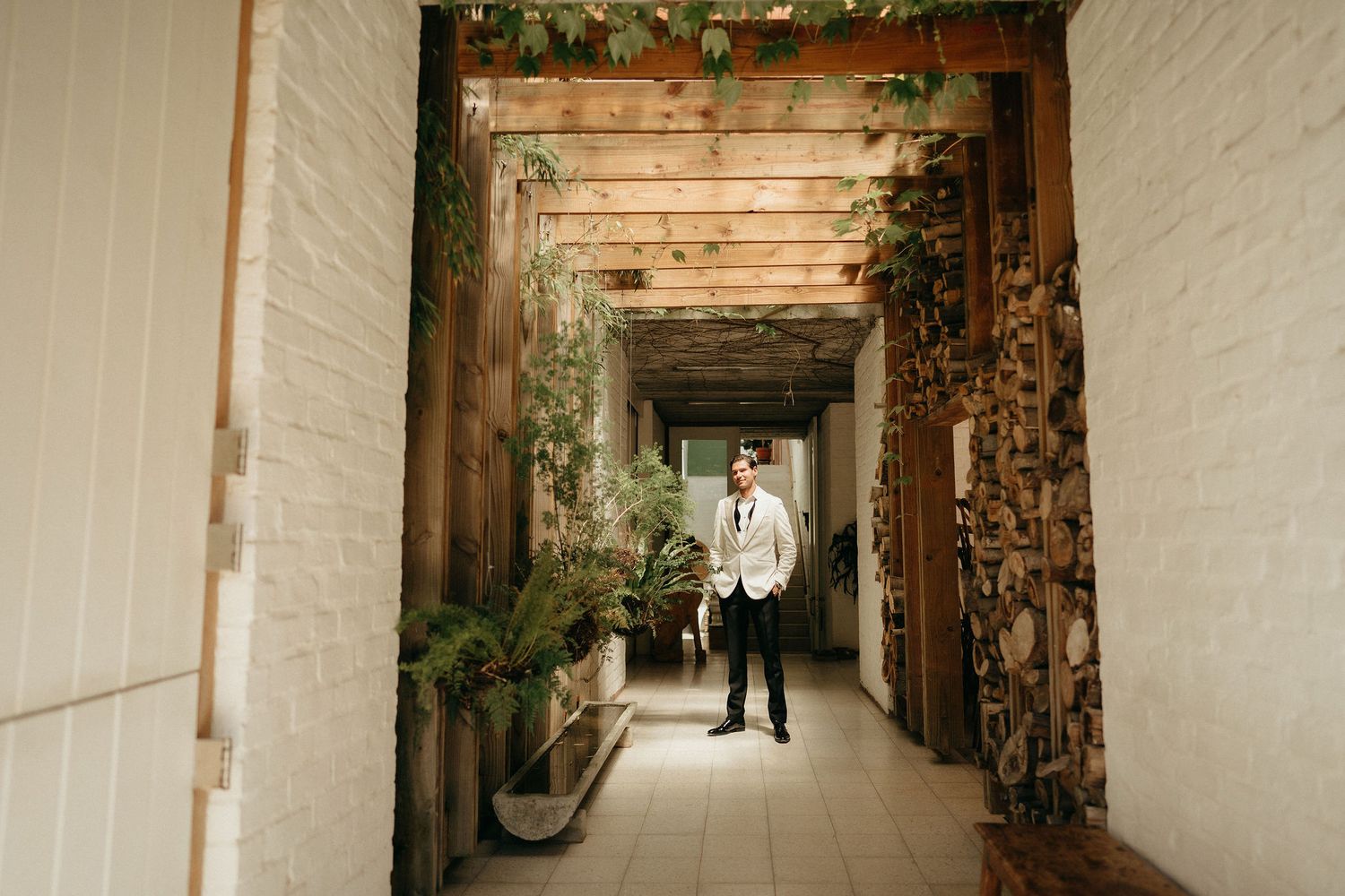 Rustic outdoor walkway with wooden beams overhead and stone walls creates a charming garden pathway atmosphere.