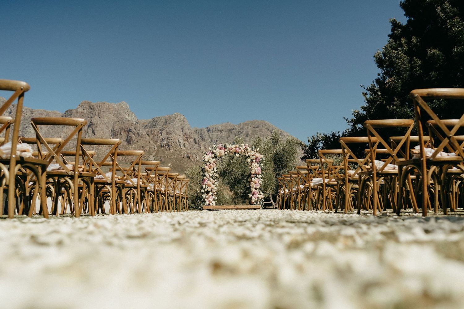 A panoramic view of wooden folding chairs arranged in rows with rocky mountain peaks in the background.