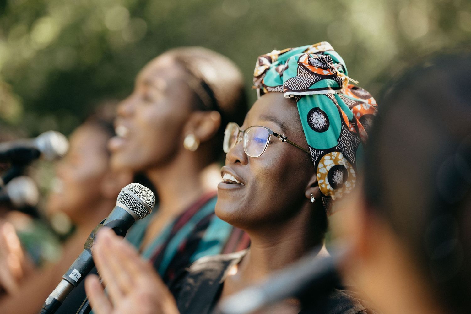 A group of performers singing together with passion and joy while holding microphones during a musical performance.