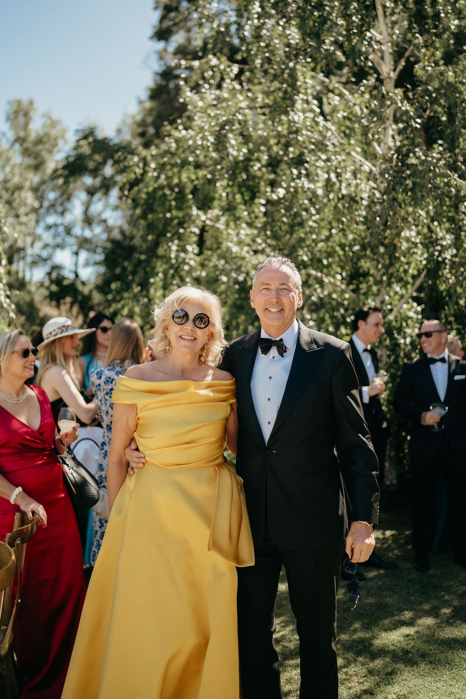 A series of candid moments at an outdoor wedding celebration with guests in formal attire including yellow and red dresses.