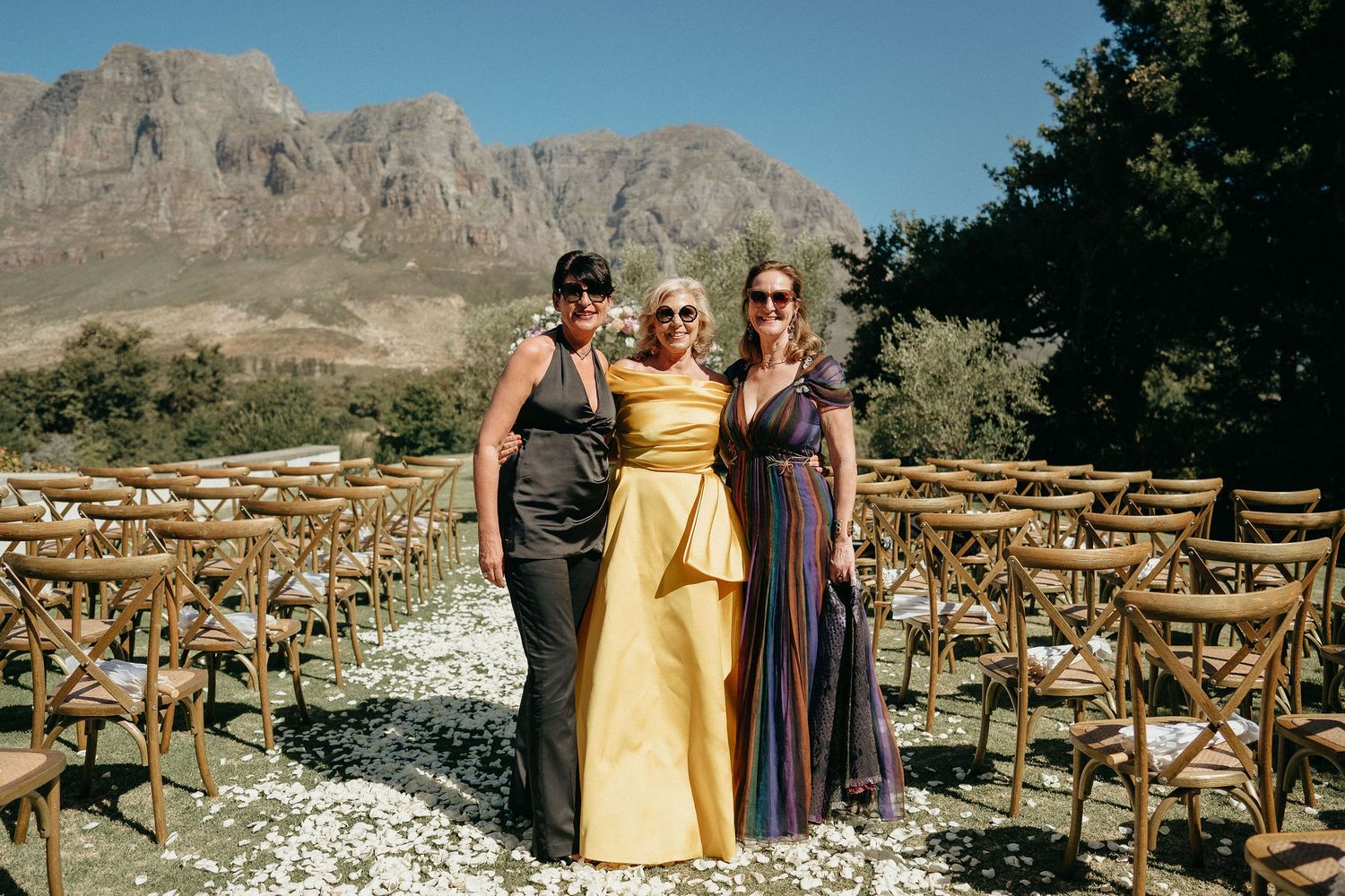Outdoor wedding ceremony setup with wooden chairs and mountain backdrop in desert landscape.