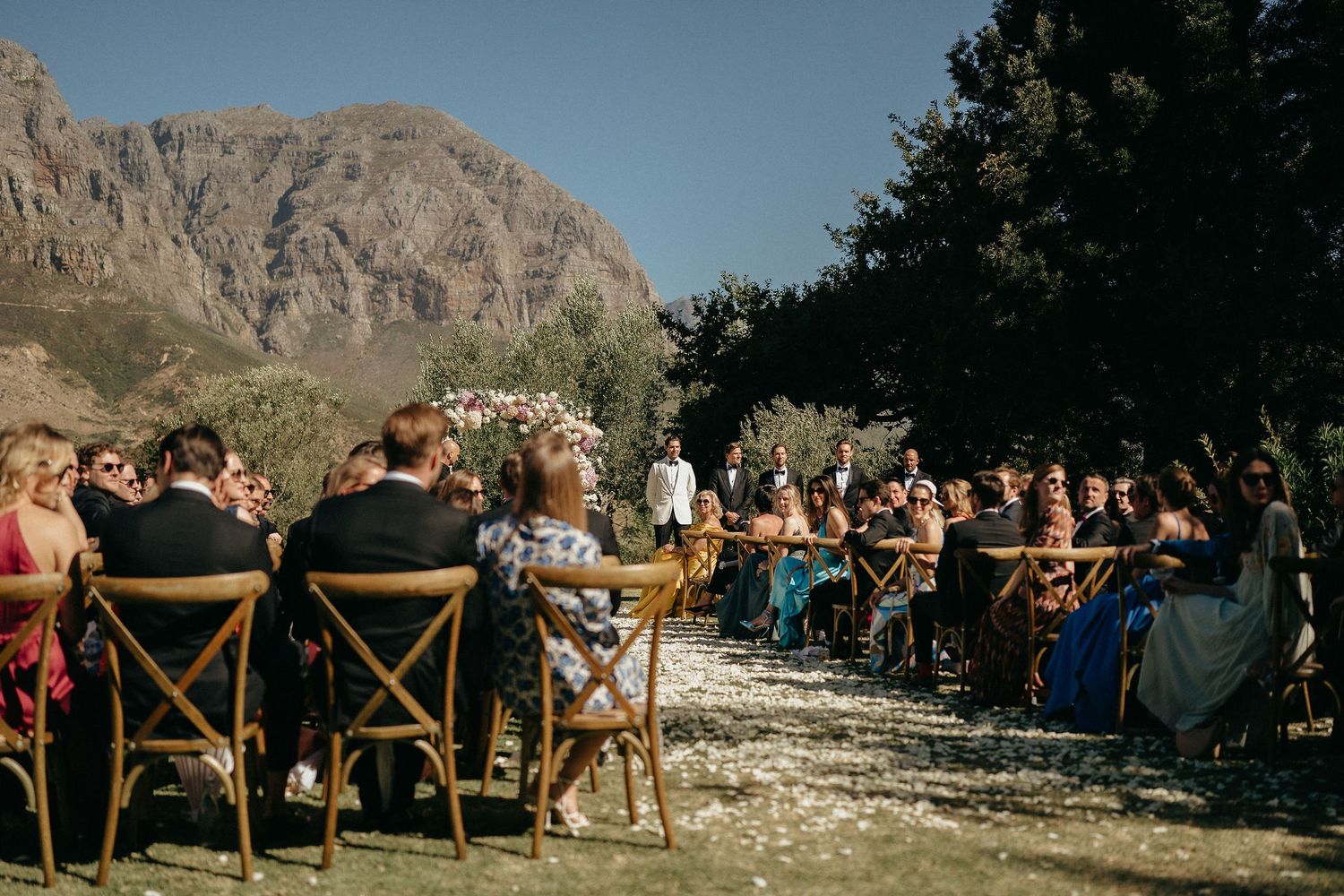 Outdoor wedding ceremony setup with wooden chairs facing mountain views in a natural desert landscape.