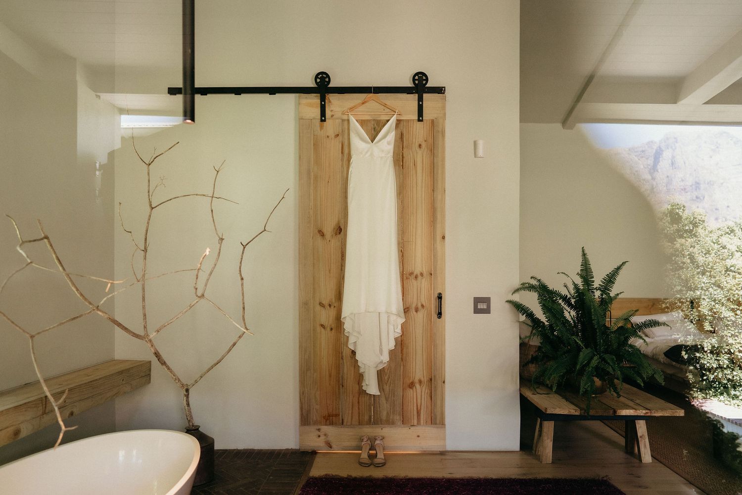 Modern farmhouse bathroom features sliding barn door, white walls, and natural wood accents with rustic design elements.