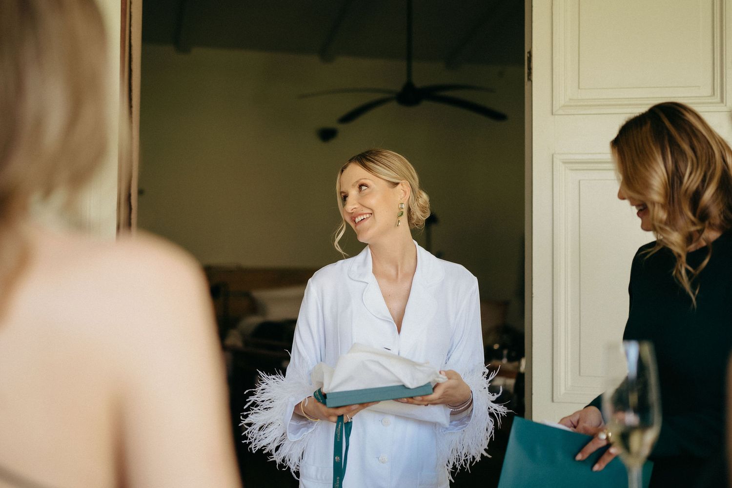 A series of candid wedding preparation moments showing white robes and dresses in a light-filled room.