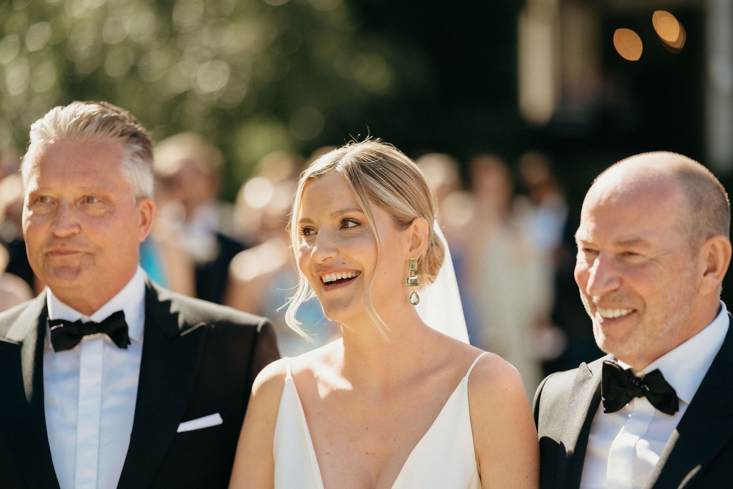 A candid moment captured during an outdoor wedding ceremony showing guests and attendees in formal attire.