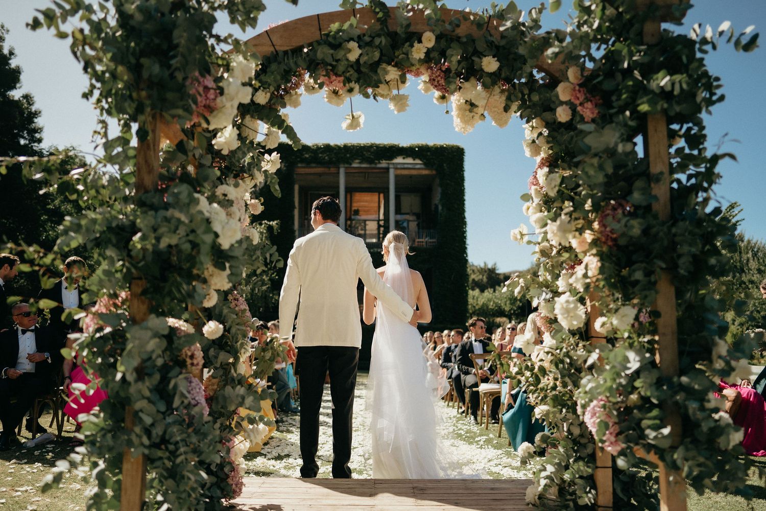 A series of wedding ceremony photos showing couples under a floral arch during an outdoor celebration.
