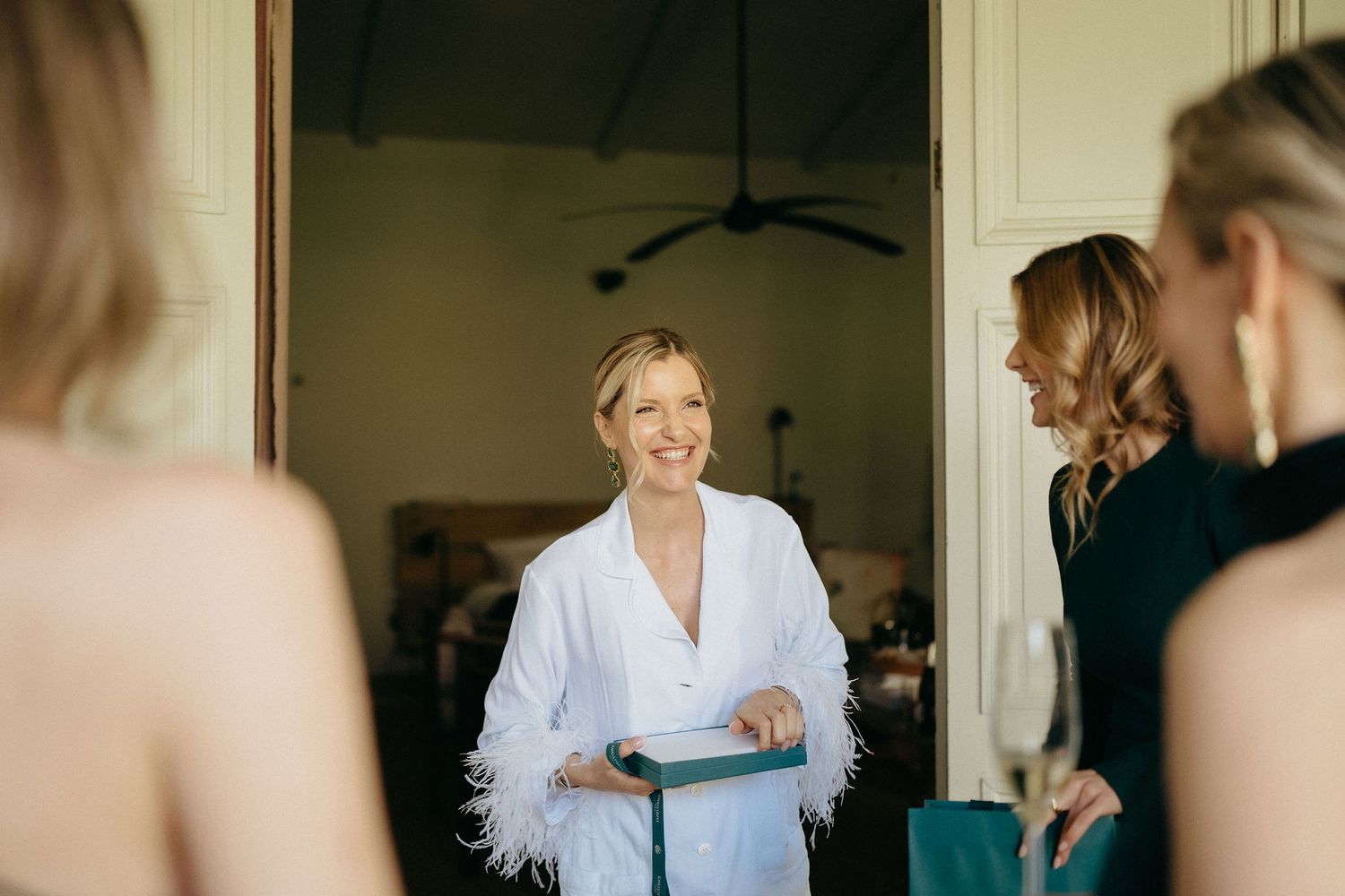 A person in a white robe smiles and gets ready in a brightly lit room during morning preparations.