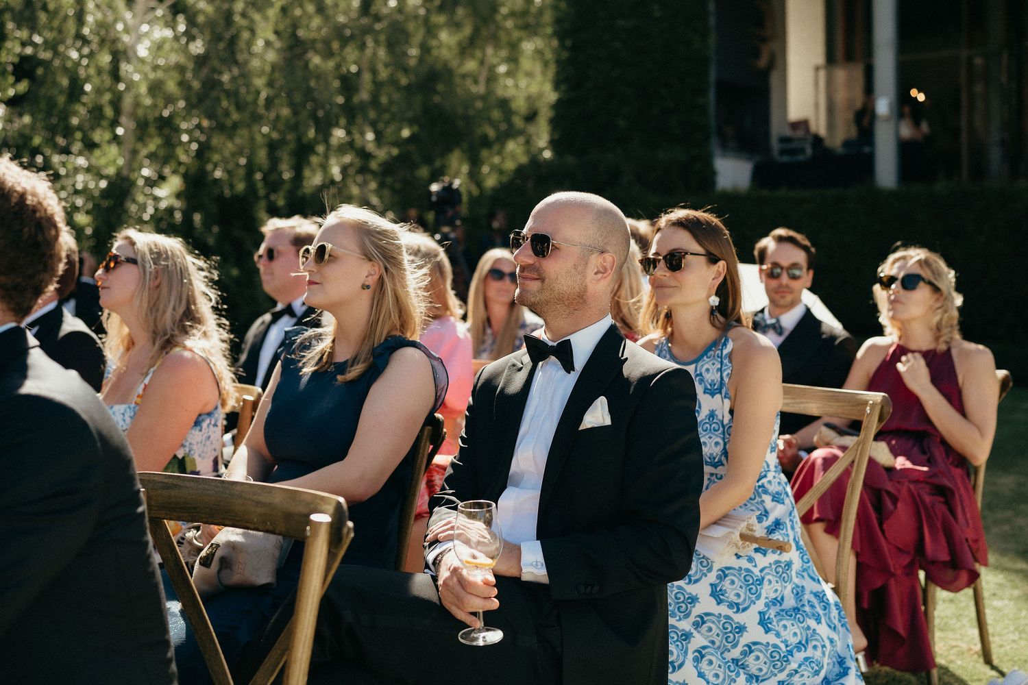 Wedding guests raise their glasses in a celebratory toast during an outdoor reception.