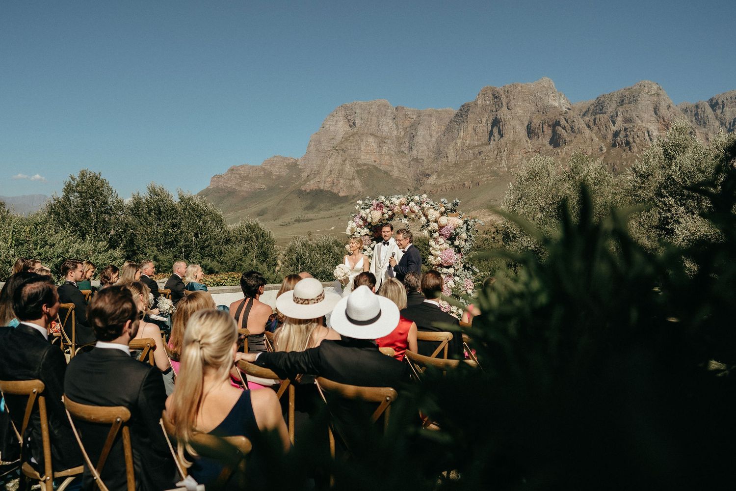 Panoramic view of rugged mountain peaks against a blue sky during an outdoor wedding ceremony.