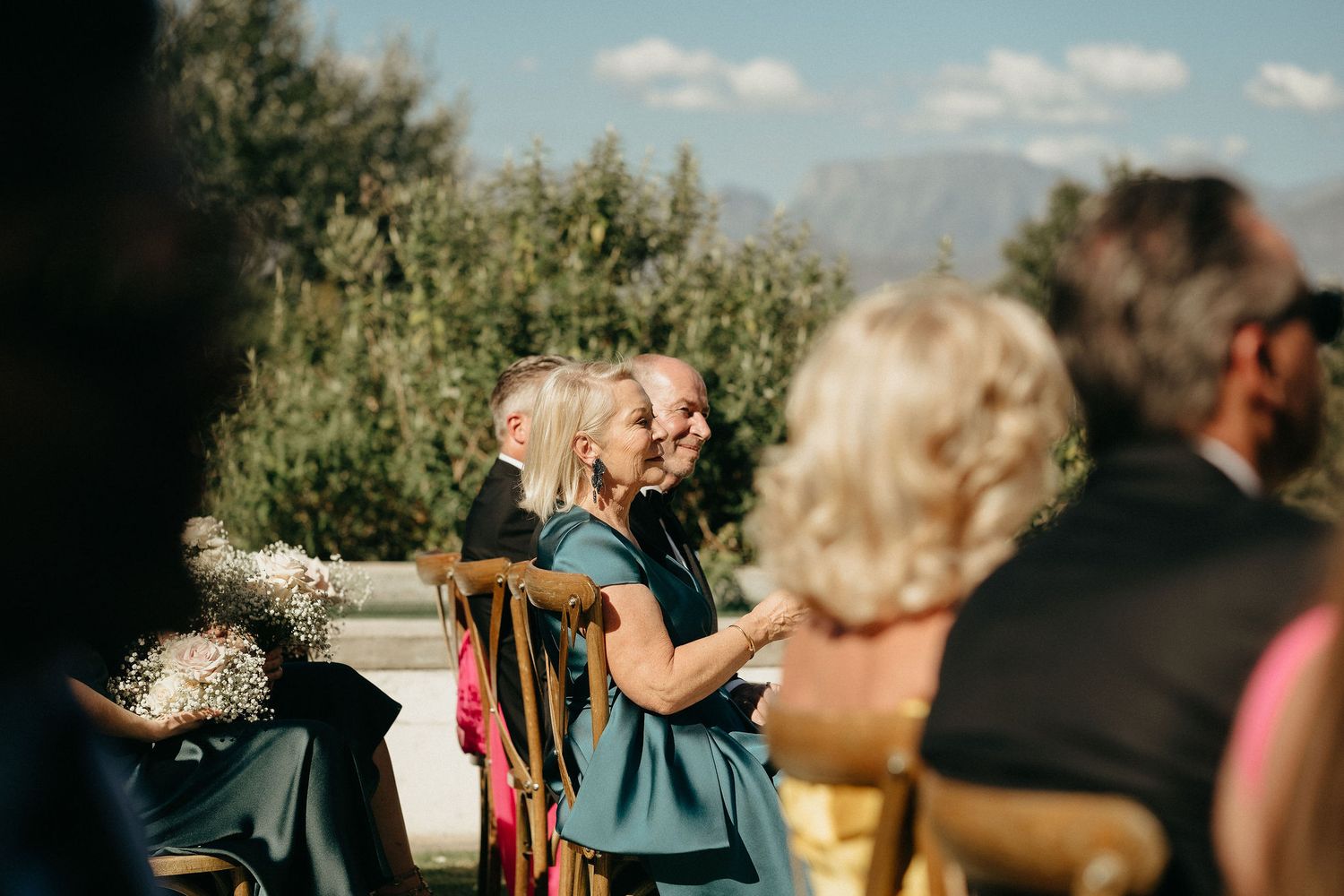 A beautiful outdoor wedding ceremony takes place in front of scenic mountain views on a sunny afternoon.