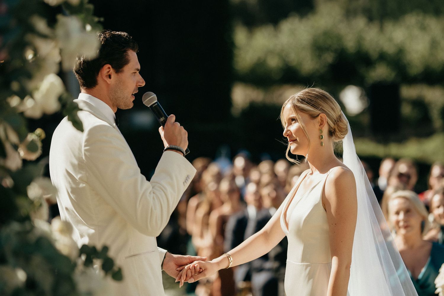 A couple shares their first dance together at an outdoor wedding reception surrounded by guests.