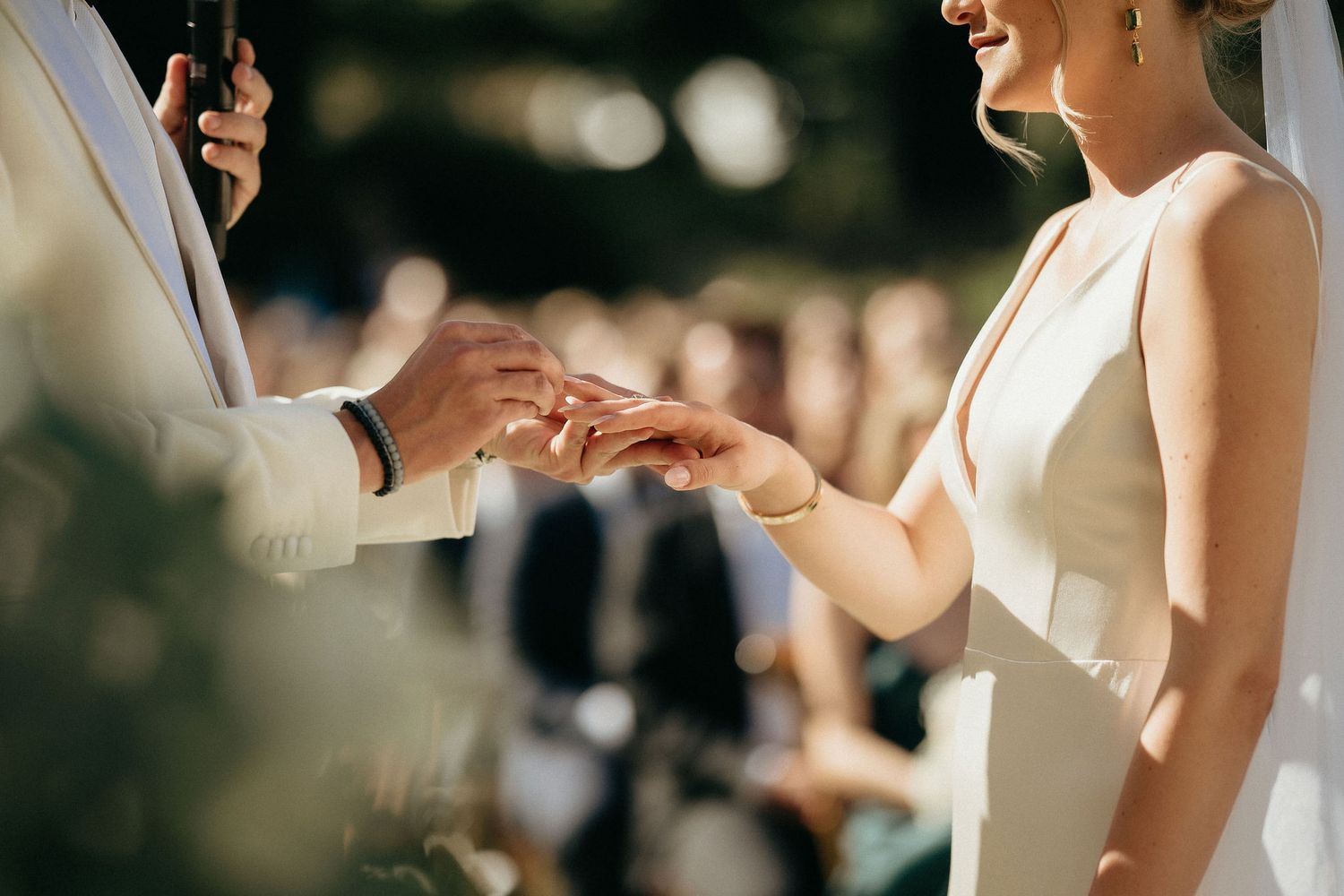 Close-up view of couple exchanging wedding rings during romantic outdoor ceremony.