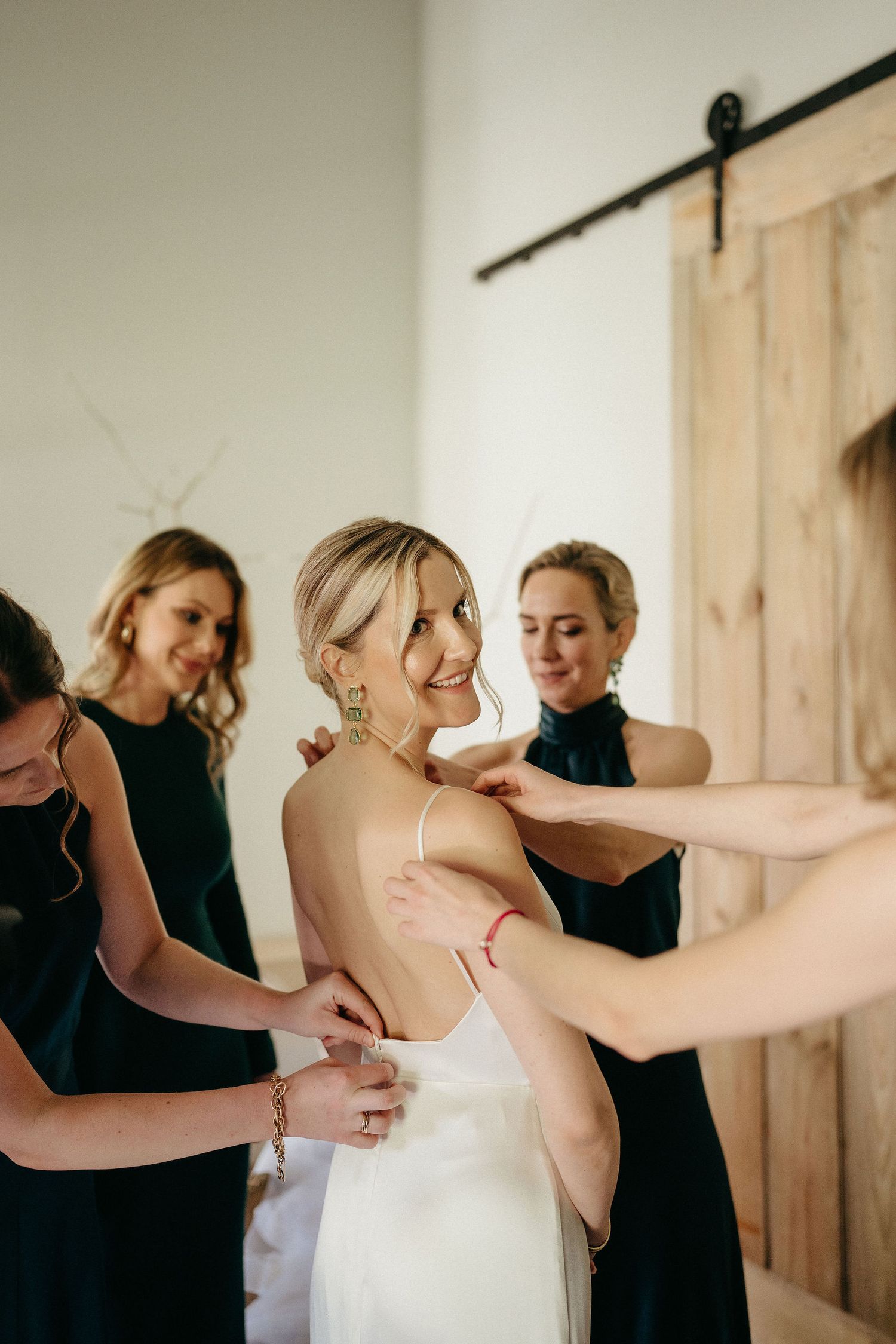 A series of photos showing the back of a wedding dress being fastened and adjusted in a bright indoor setting.