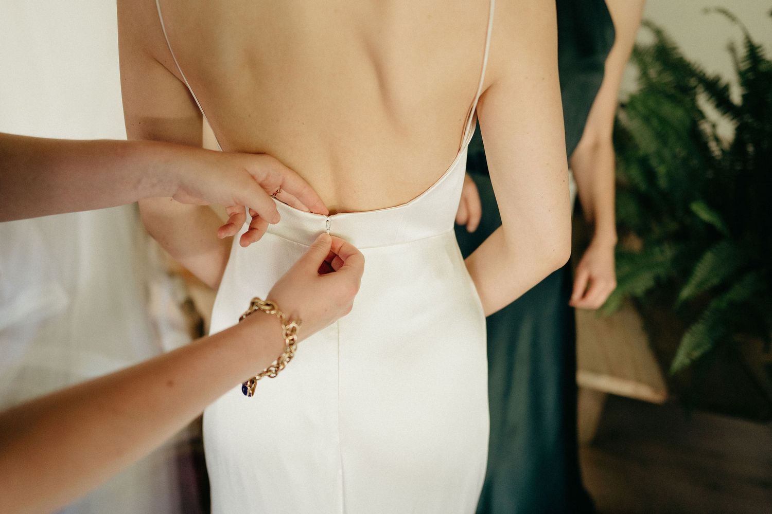 Close-up view of someone adjusting a delicate white wedding dress with lace details and buttons.