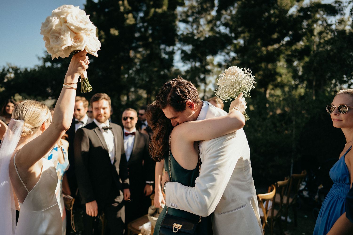 Wedding couple and guests dance joyfully during outdoor sunset reception celebration.