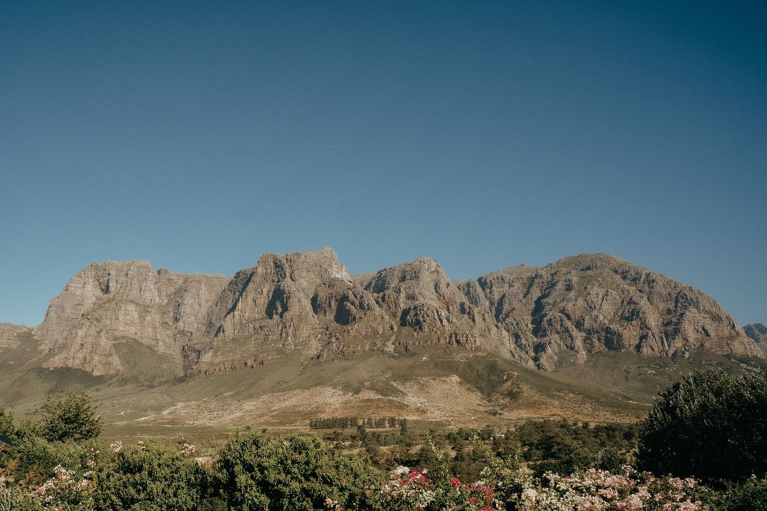 Panoramic view of rugged desert mountains with jagged peaks against a clear blue sky in the southwestern landscape.