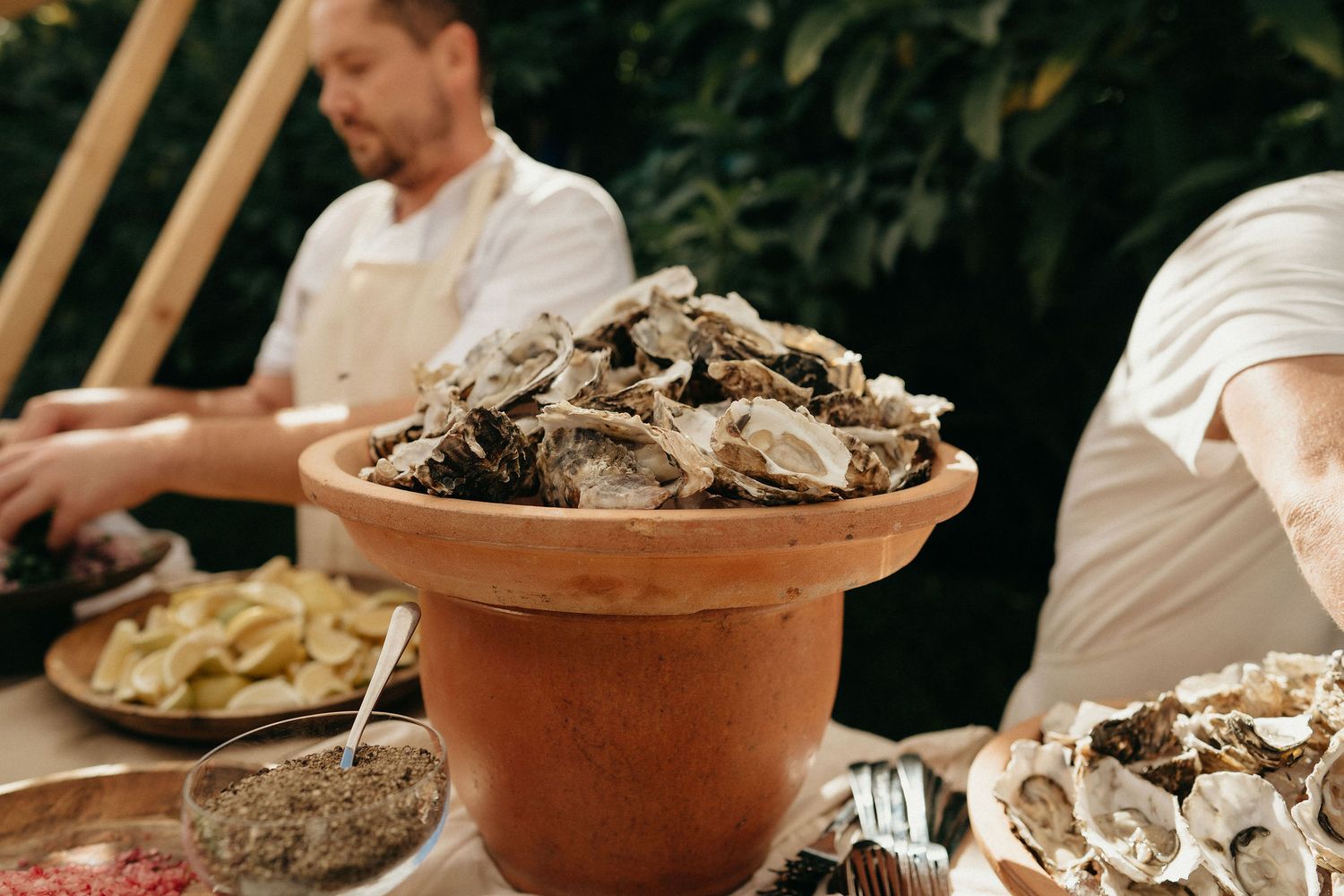 Fresh oysters on ice being served at a seafood restaurant with terracotta bowls and garnishes.