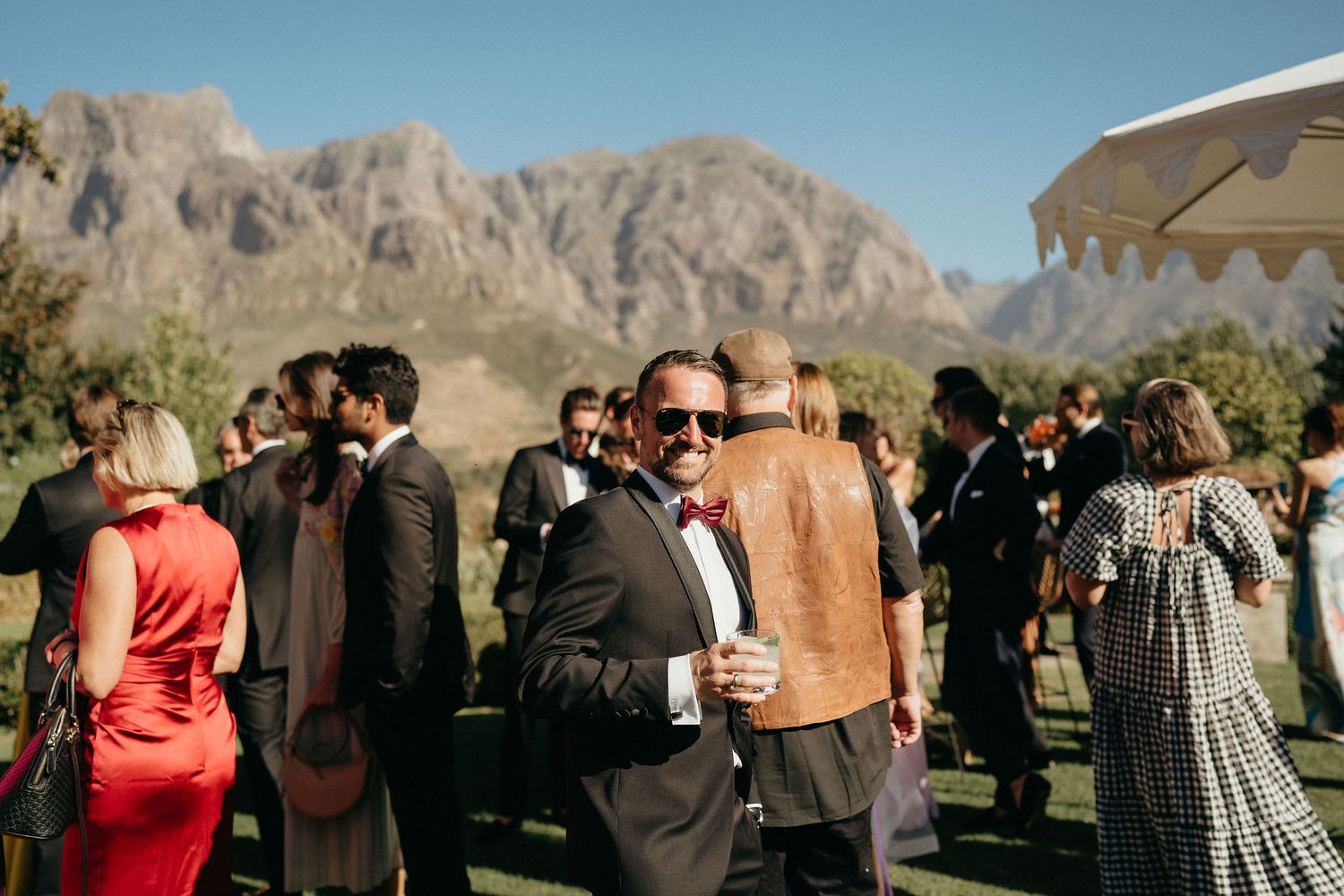 Wedding guests gather for an outdoor celebration with rugged mountain peaks creating a dramatic desert backdrop.
