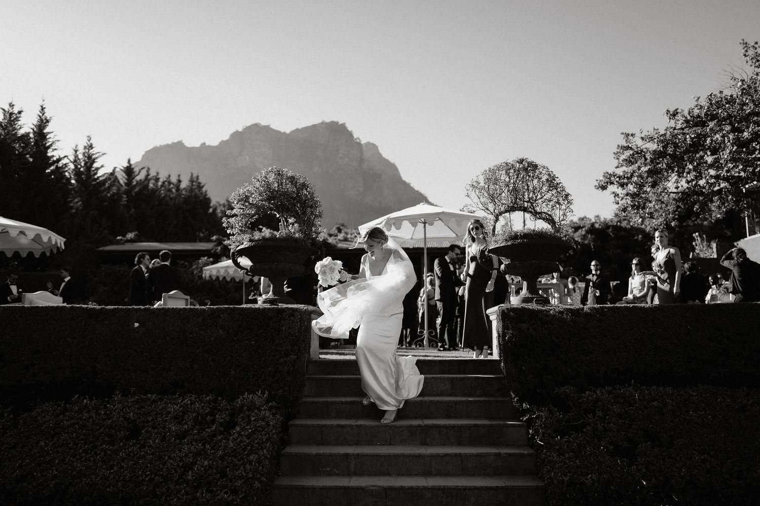 A panoramic series of black and white wedding celebration scenes with mountains in the background.