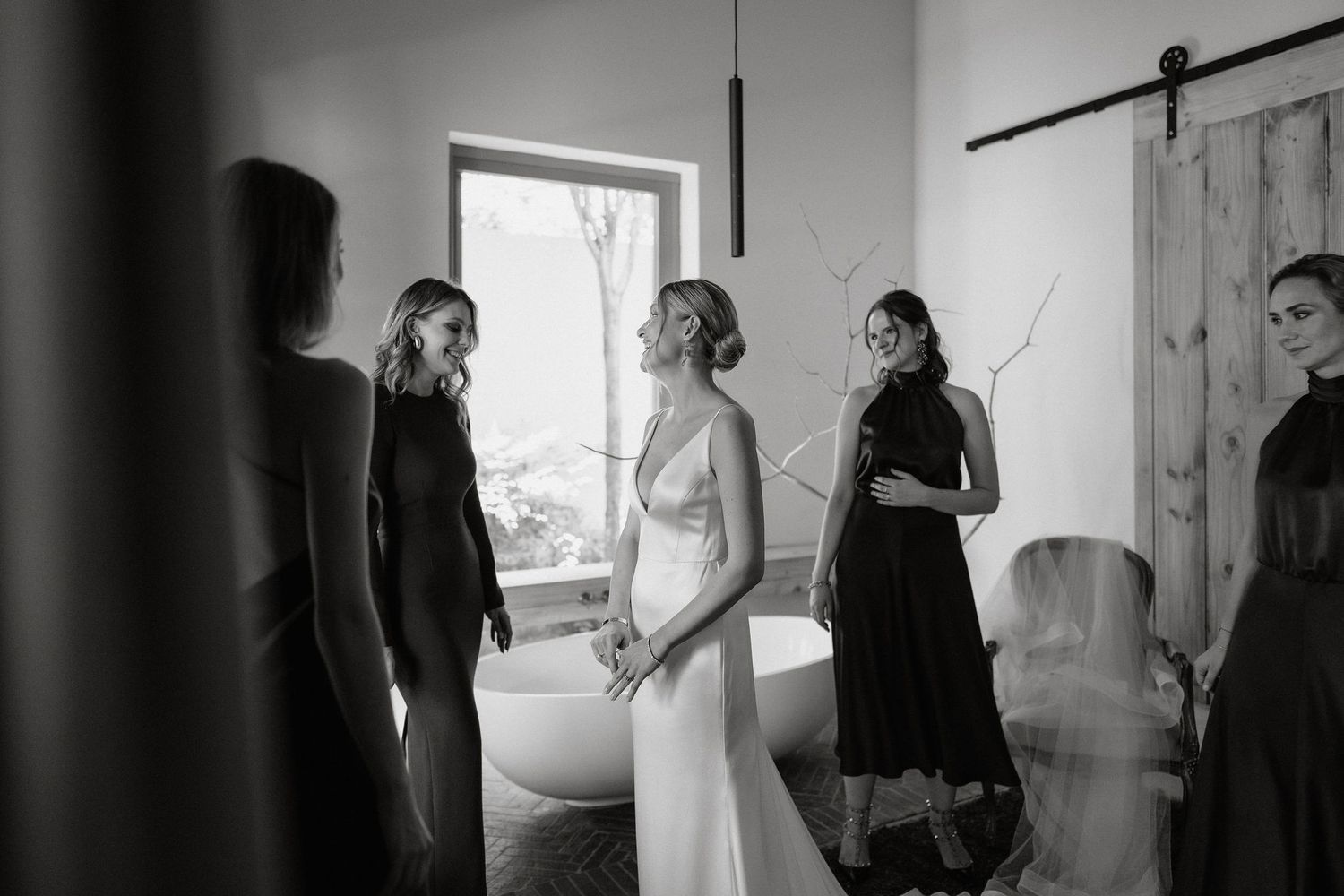 Black and white wedding preparation photos showing moments of getting ready with bridesmaids and wedding dress details.