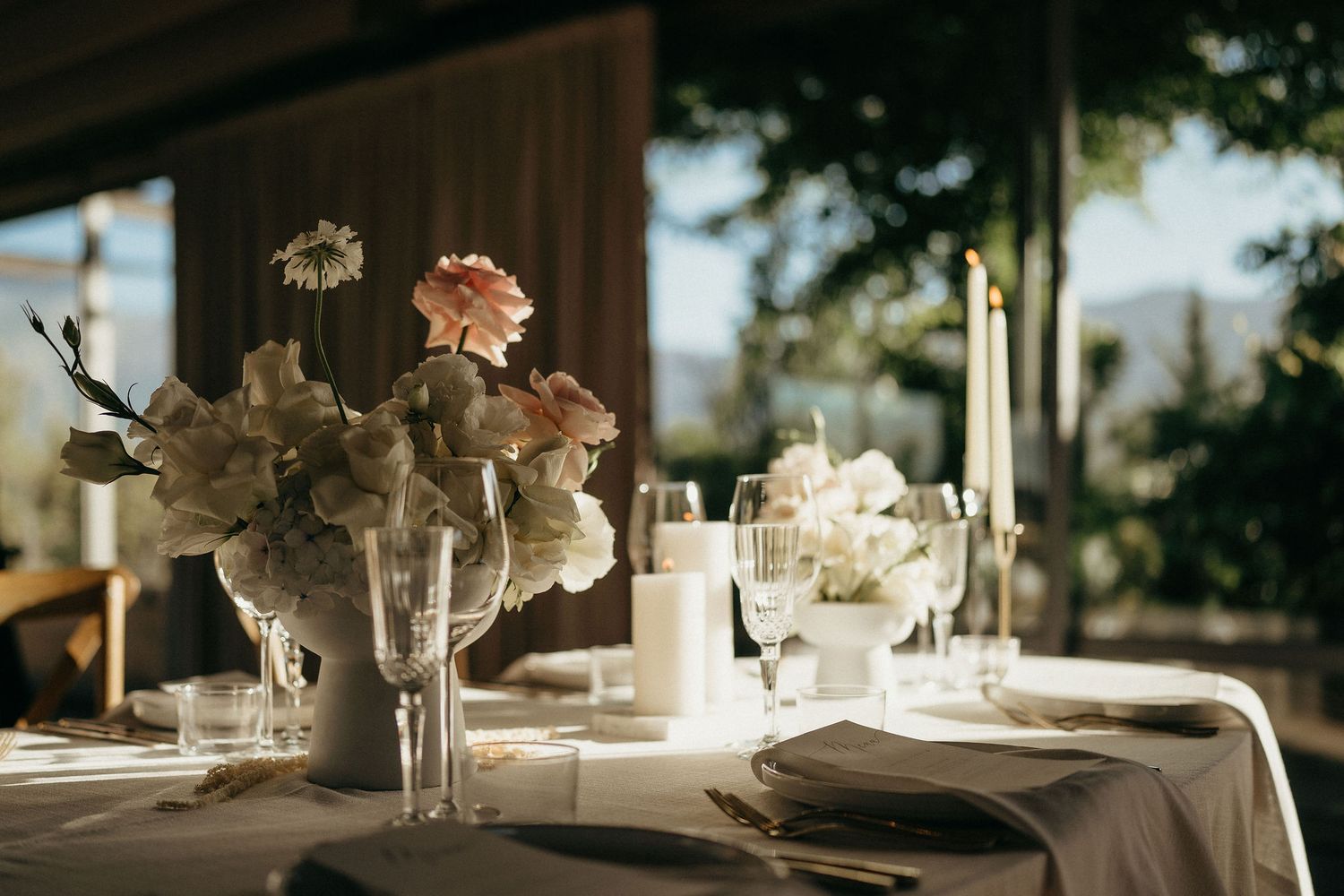Elegant table settings with white floral centerpieces and candles create a romantic wedding reception atmosphere.