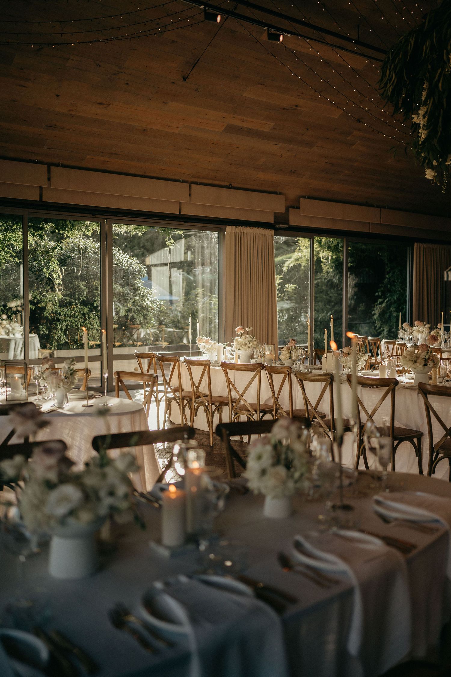 Elegant wedding reception venue with wooden ceiling and tables set with white linens and floral centerpieces.