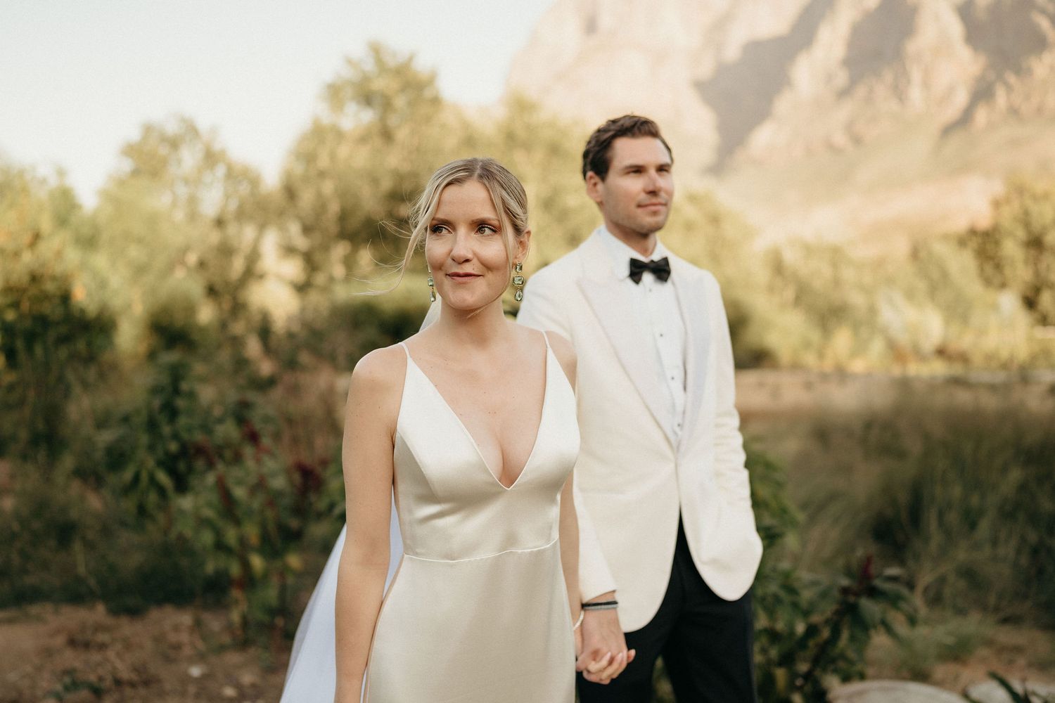 Elegant wedding portraits captured in front of rugged mountain peaks during golden hour.