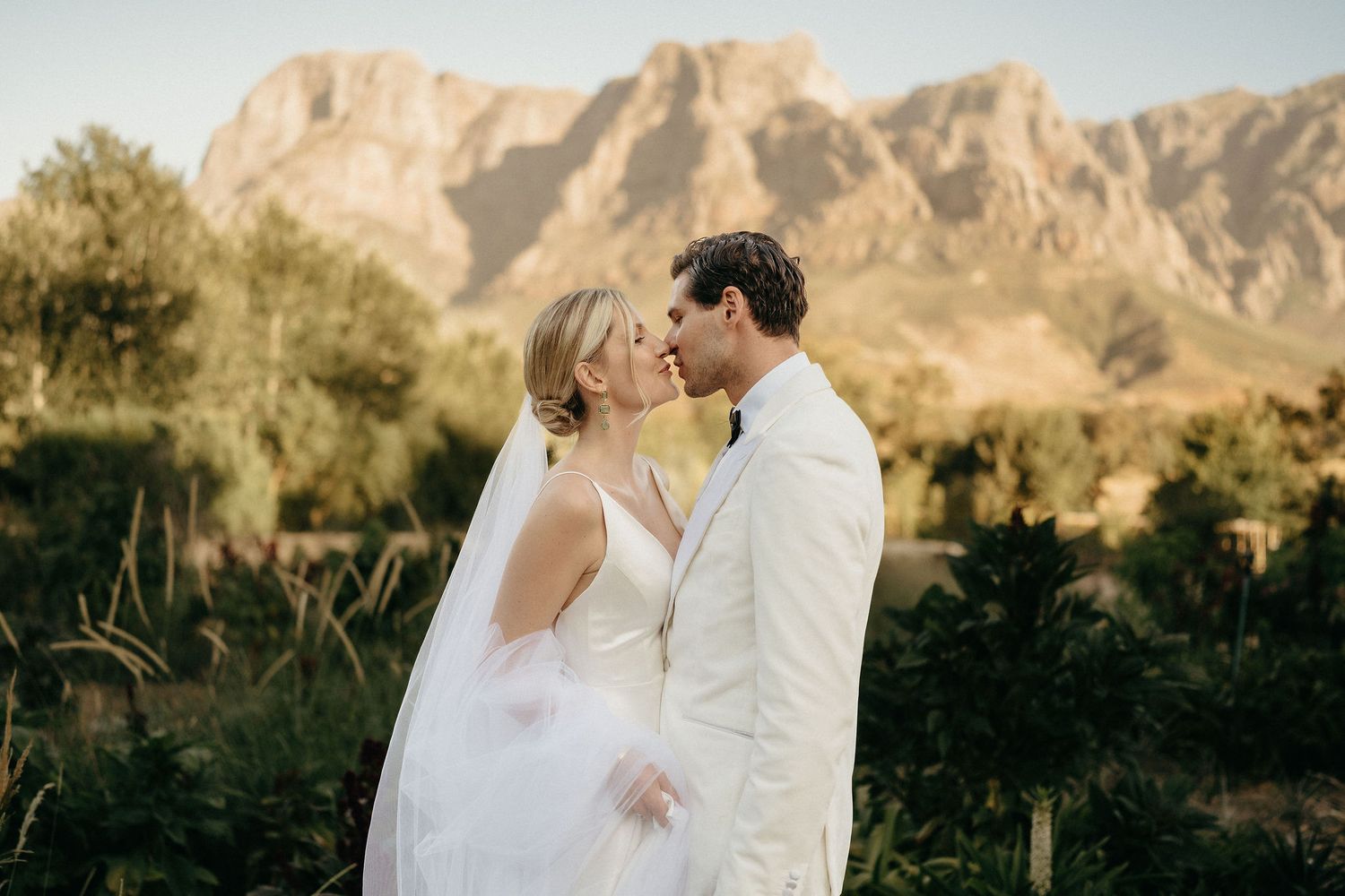 Newlyweds share intimate moments with stunning desert mountain landscape as their backdrop.