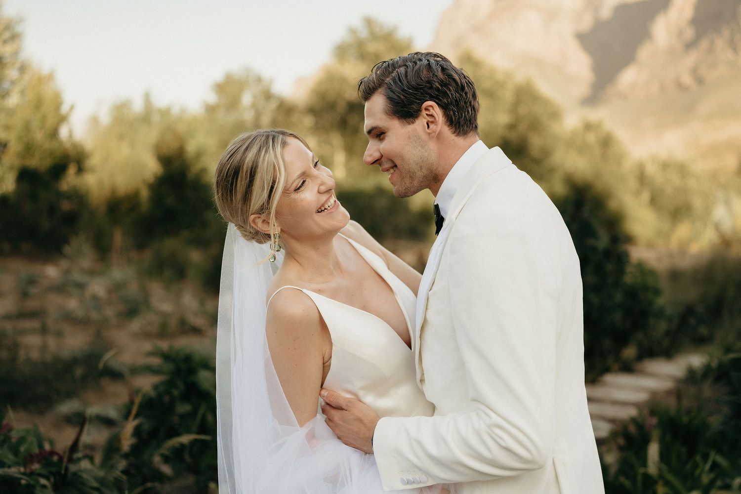A bride and groom share intimate moments in a series of romantic outdoor wedding photos at sunset.