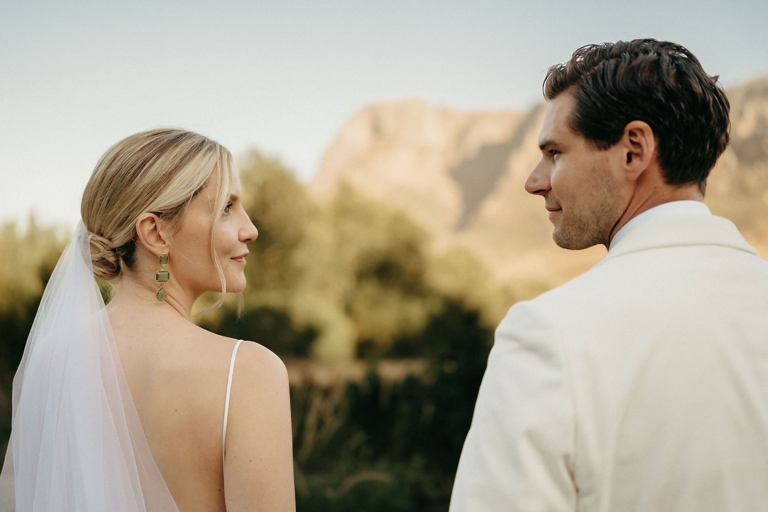 Romantic wedding couple shares intimate moments during golden hour outdoor photo session.