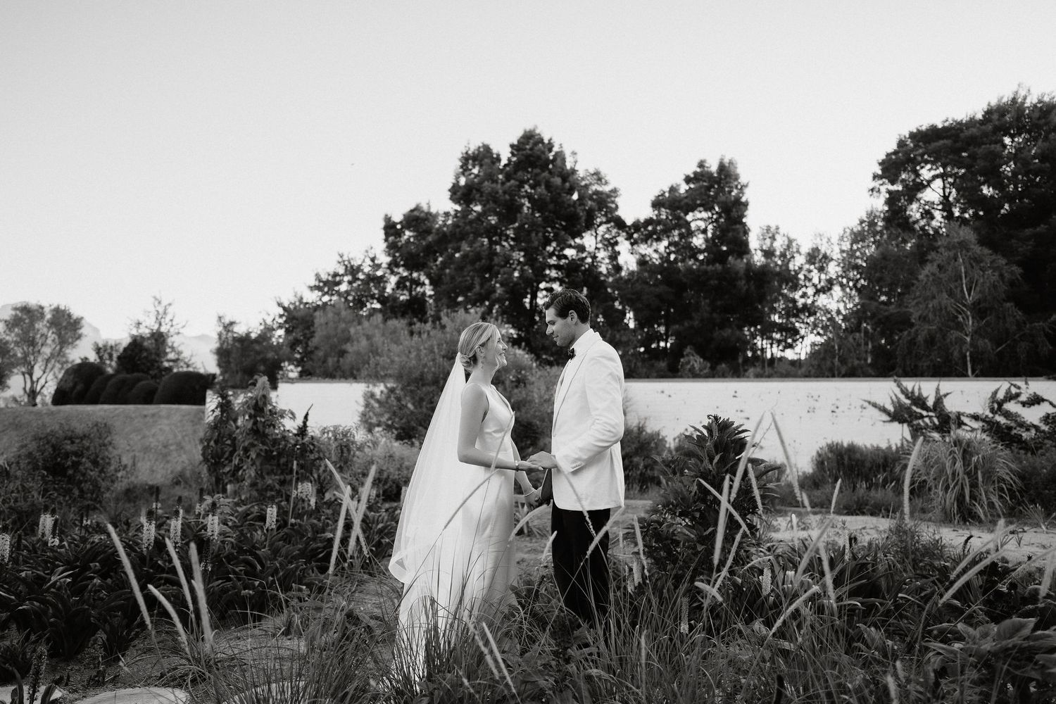 Black and white panoramic photo series showing a couple in wedding attire posing together in a scenic outdoor field.