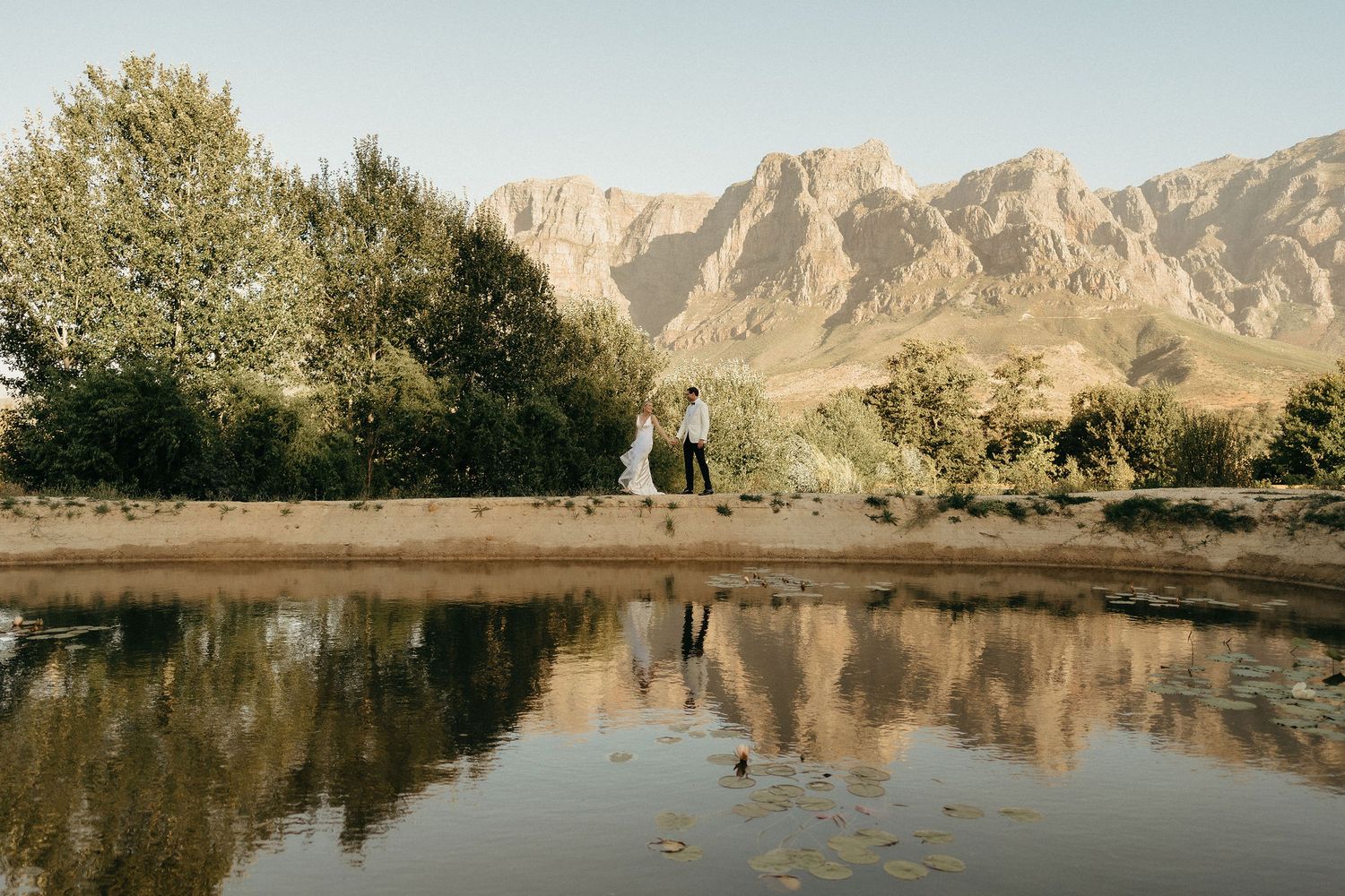 Panoramic view of rugged mountain peaks reflected in a tranquil lake with trees along the shoreline.