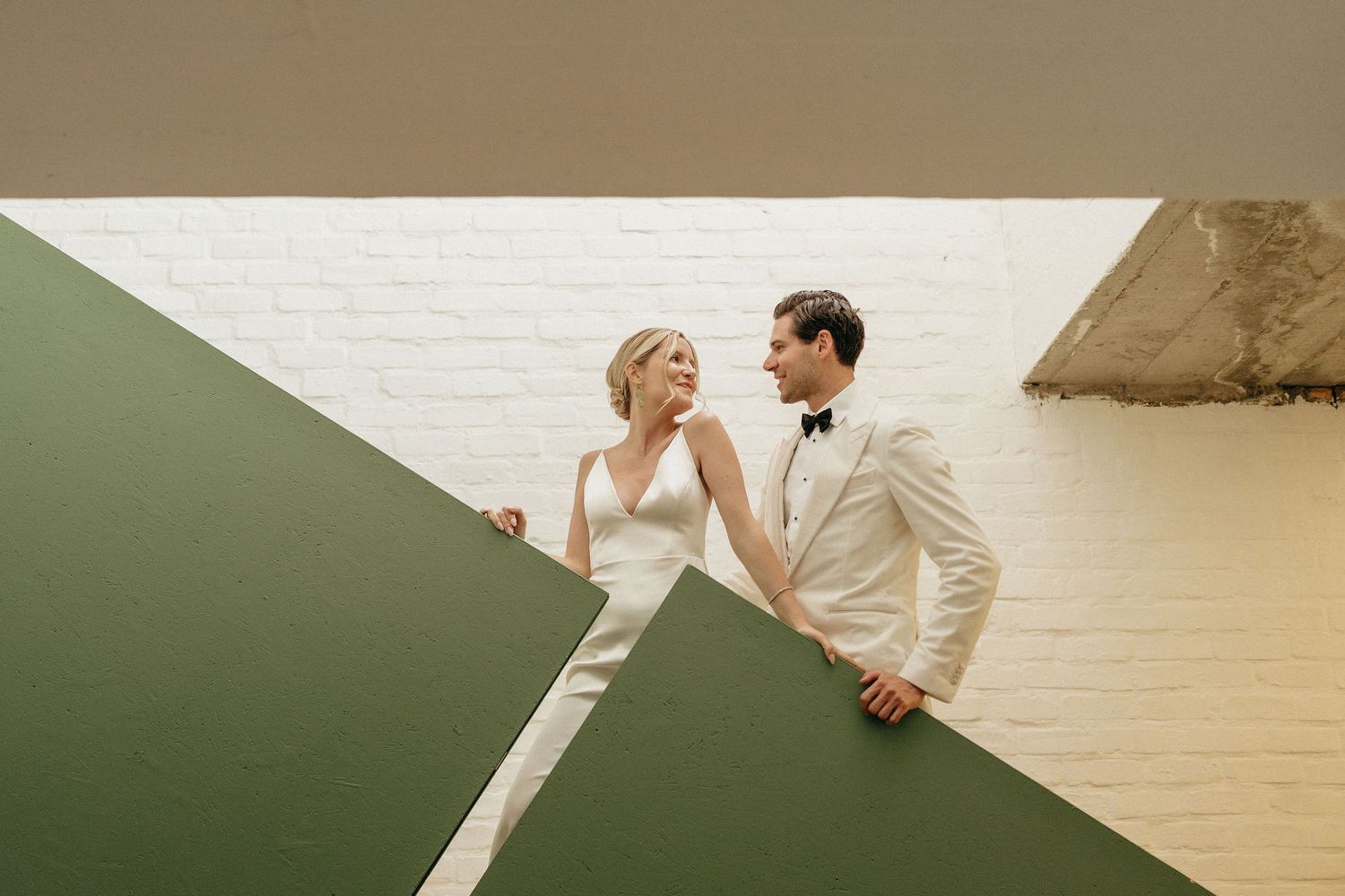 A couple in wedding attire dances gracefully together on a wooden floor during their first dance.